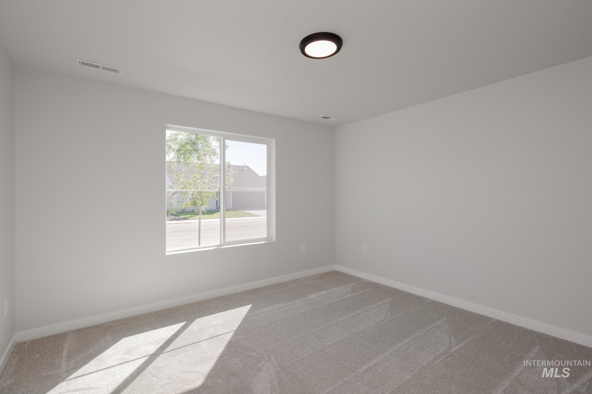 Spare room featuring light carpet and baseboards