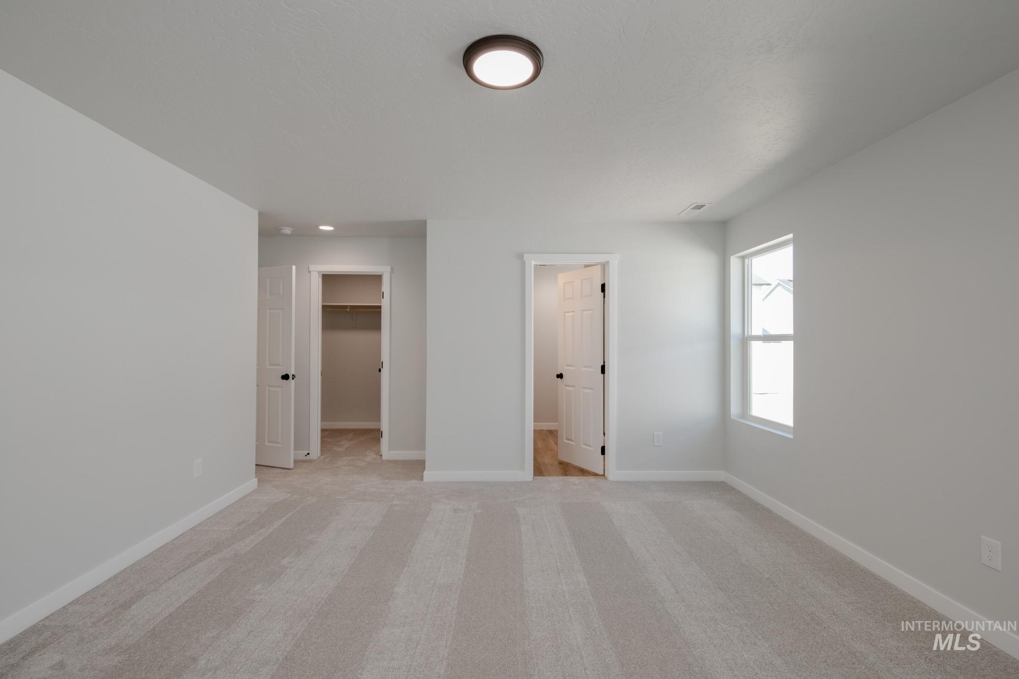 Unfurnished bedroom featuring a walk in closet and light colored carpet