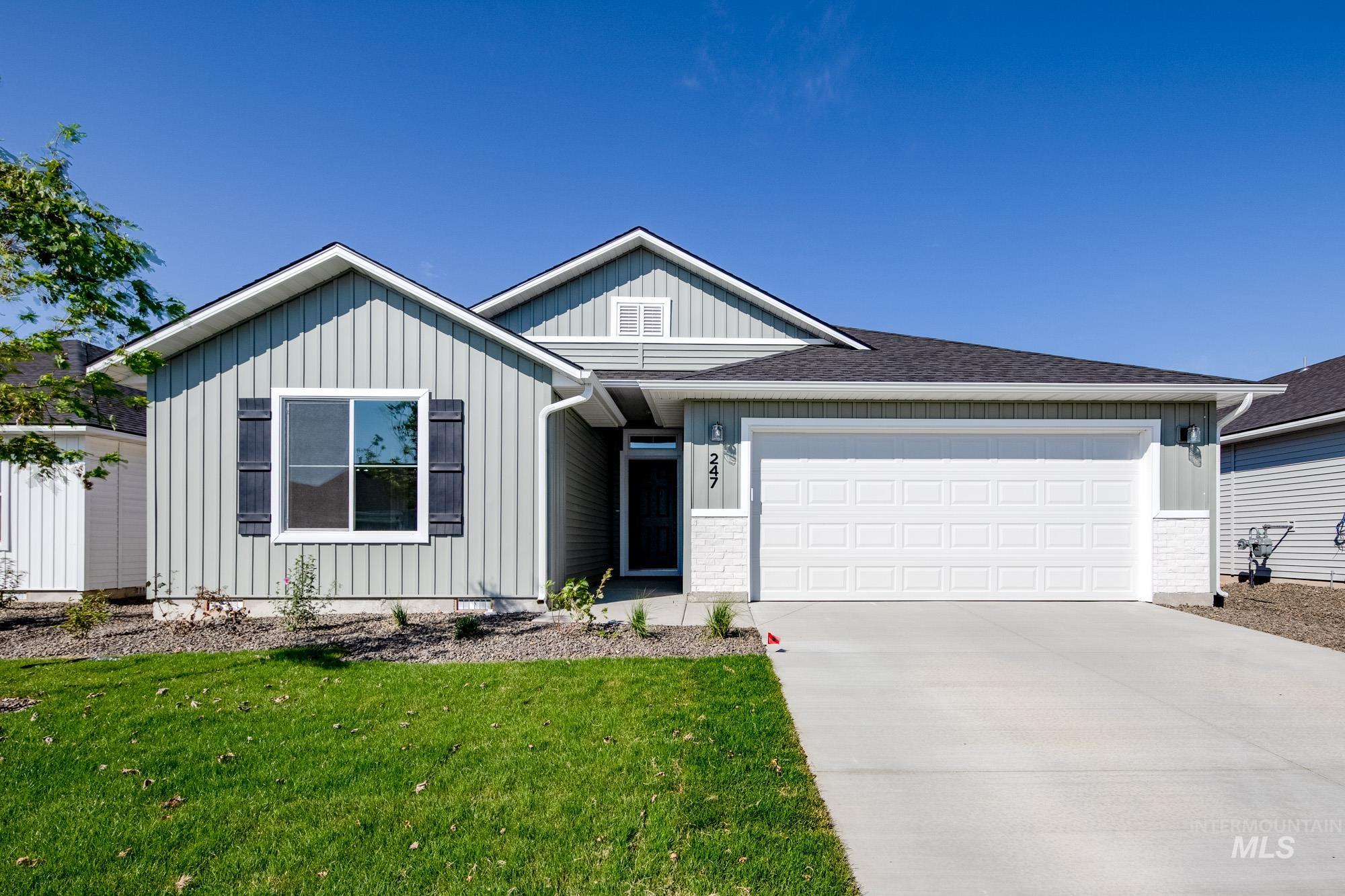 Ranch-style house featuring board and batten siding, an attached garage, a front yard, driveway, and a shingled roof