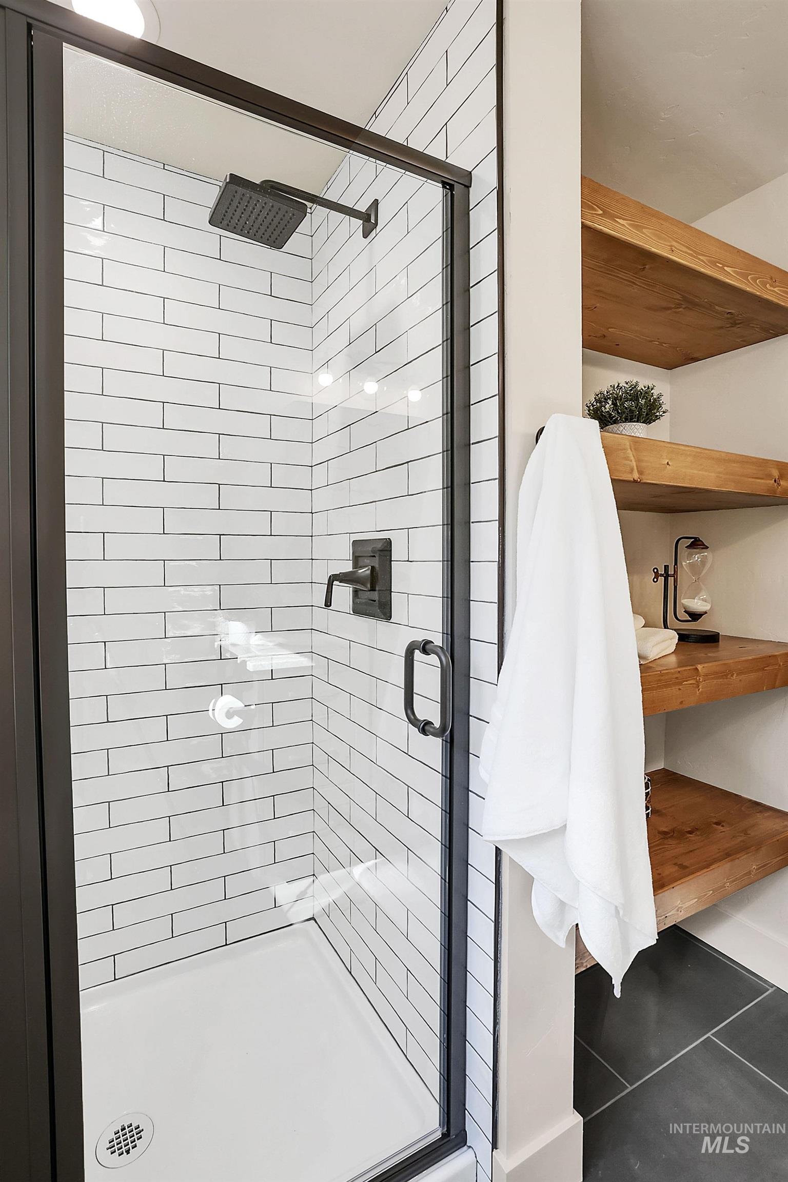Full bathroom with a stall shower and dark tile patterned flooring