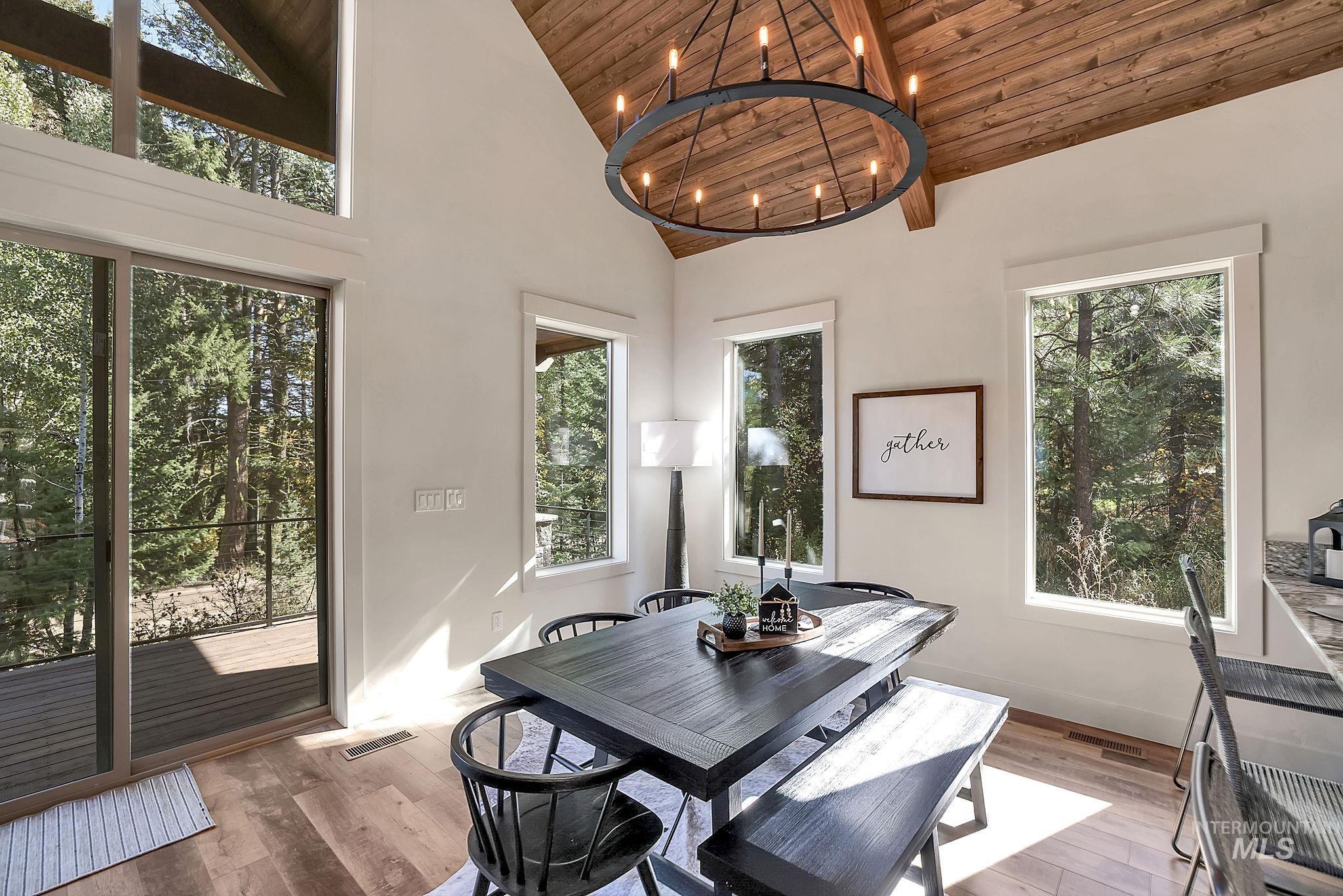Dining space featuring wood finished floors, wooden ceiling, a chandelier, healthy amount of natural light, and high vaulted ceiling
