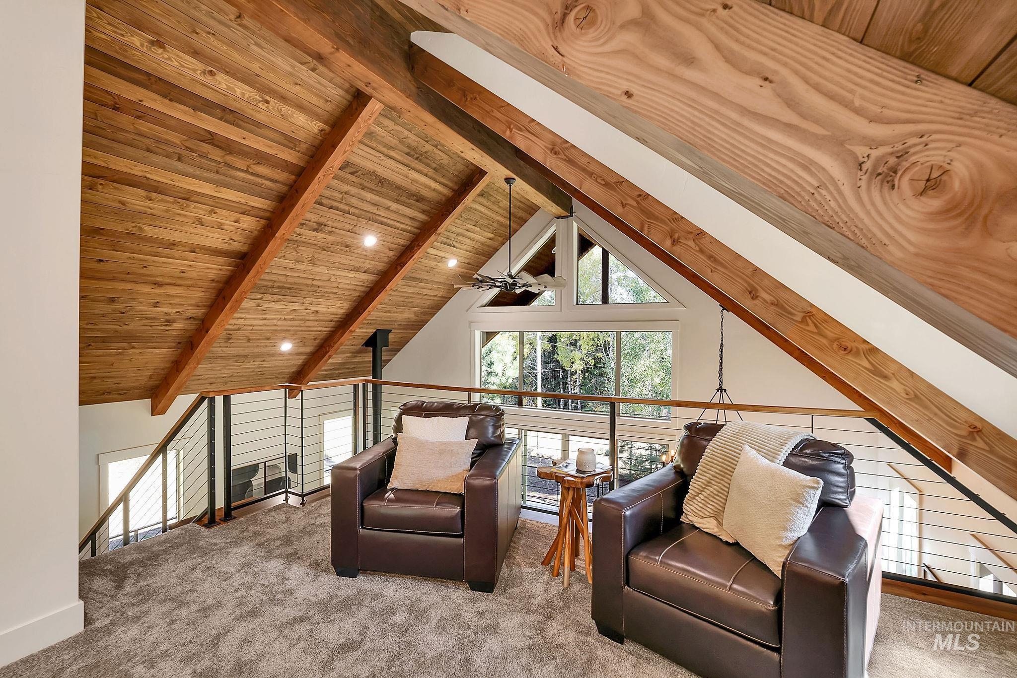 Living area featuring an upstairs landing, a wood ceiling with exposed beams, carpet flooring, high vaulted ceiling, and a ceiling fan