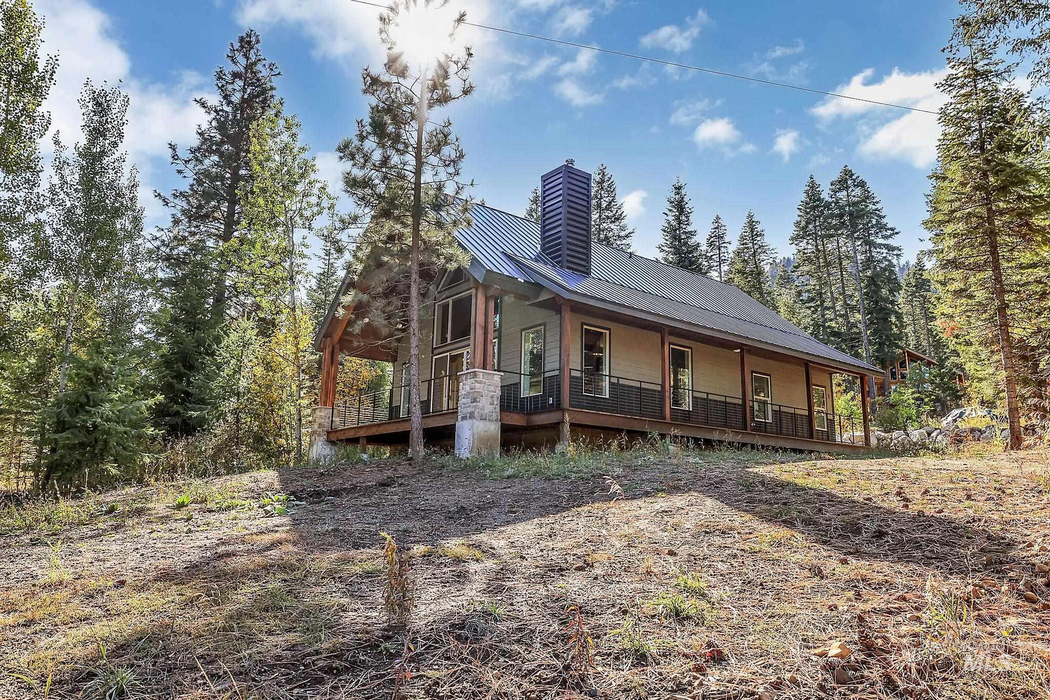 View of front facade featuring a metal roof, a porch, a chimney, and a forest view