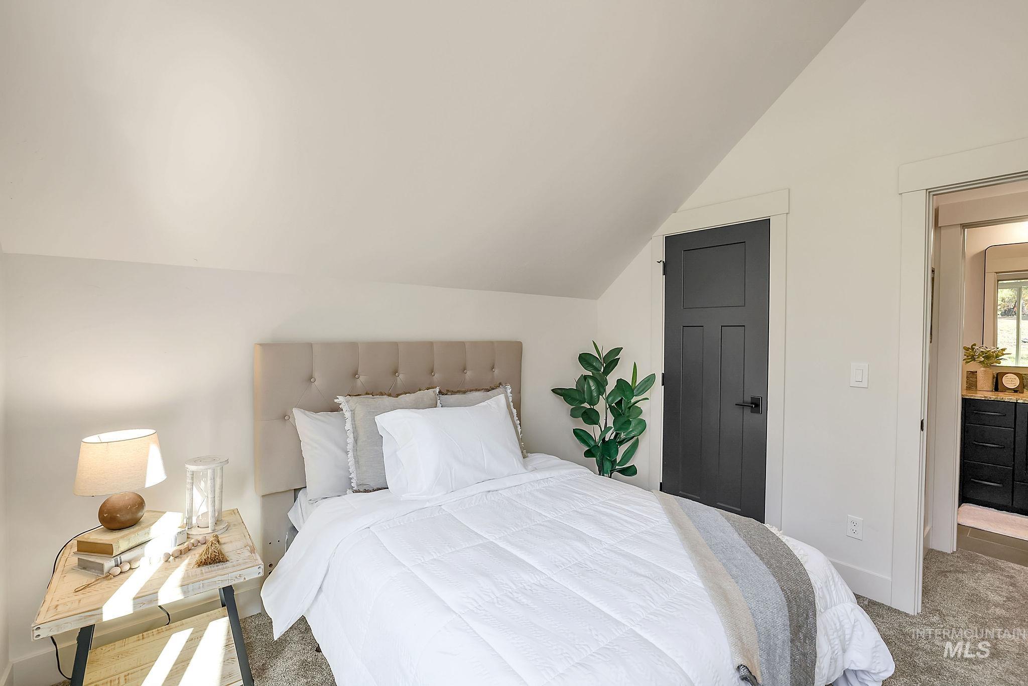 Carpeted bedroom featuring vaulted ceiling and baseboards