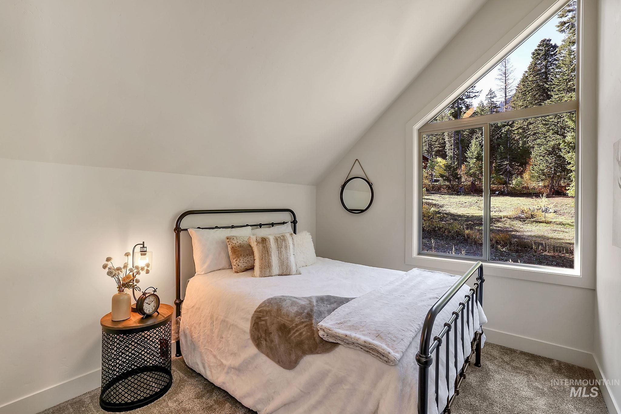 Carpeted bedroom with lofted ceiling and baseboards