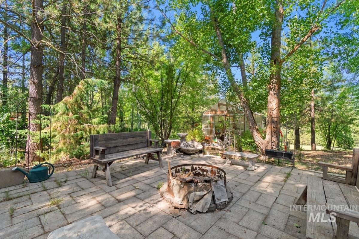 View of patio / terrace featuring a fire pit, an outdoor structure, an exterior structure, and view of wooded area