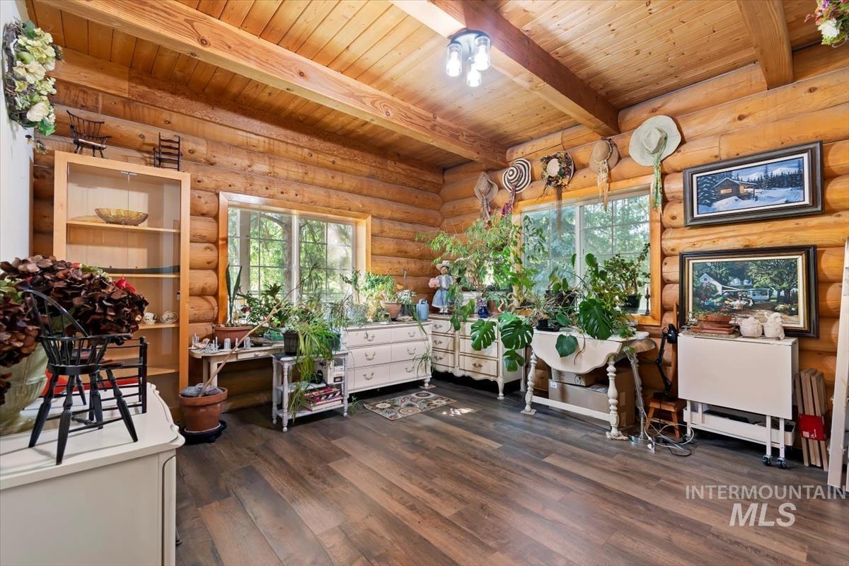 Living area with dark wood-style flooring, a wood ceiling with exposed beams, and rustic walls