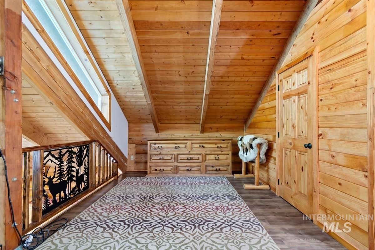 Additional living space featuring wood ceiling, dark wood finished floors, vaulted ceiling with beams, and wooden walls