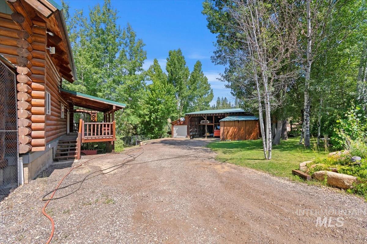 Exterior space with log siding, an outdoor structure, dirt driveway, and a deck