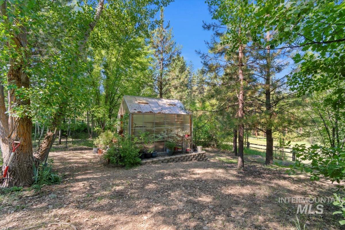 View of yard featuring an outdoor structure, an exterior structure, a sunroom, and view of scattered trees