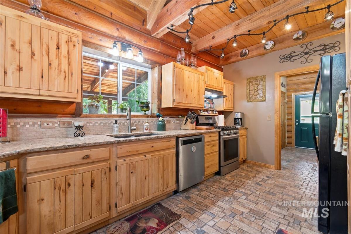 Kitchen with light wood finish cabinetry, stainless steel appliances, a wooden ceiling with exposed beams, light stone countertops, and tasteful backsplash