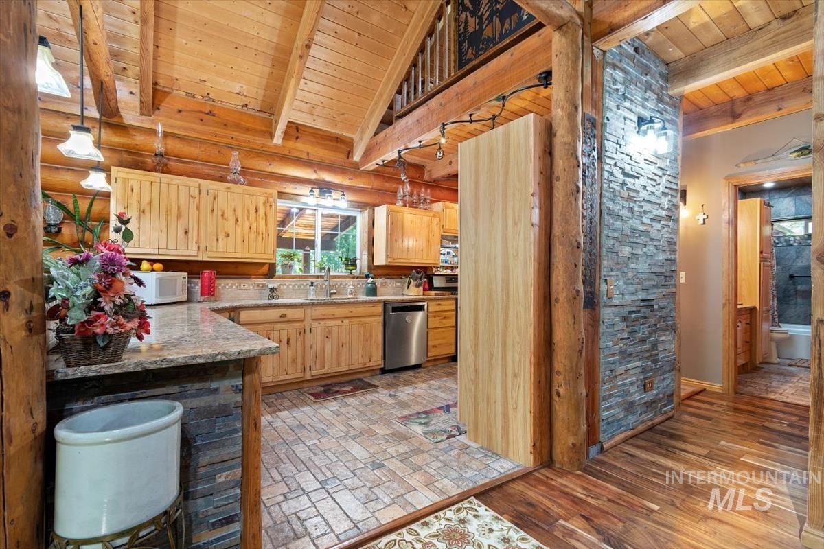 Kitchen featuring a high wooden beamed ceiling, light wood finish cabinets, dishwasher, and white microwave
