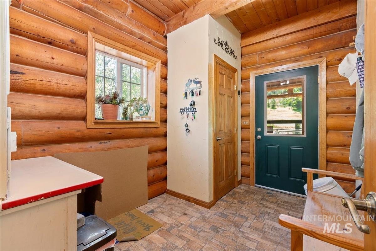 Entryway featuring rustic walls, wooden ceiling, and stone finish flooring