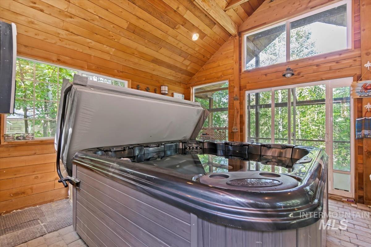 Misc room with a jacuzzi, wooden walls, and a vaulted wooden ceiling