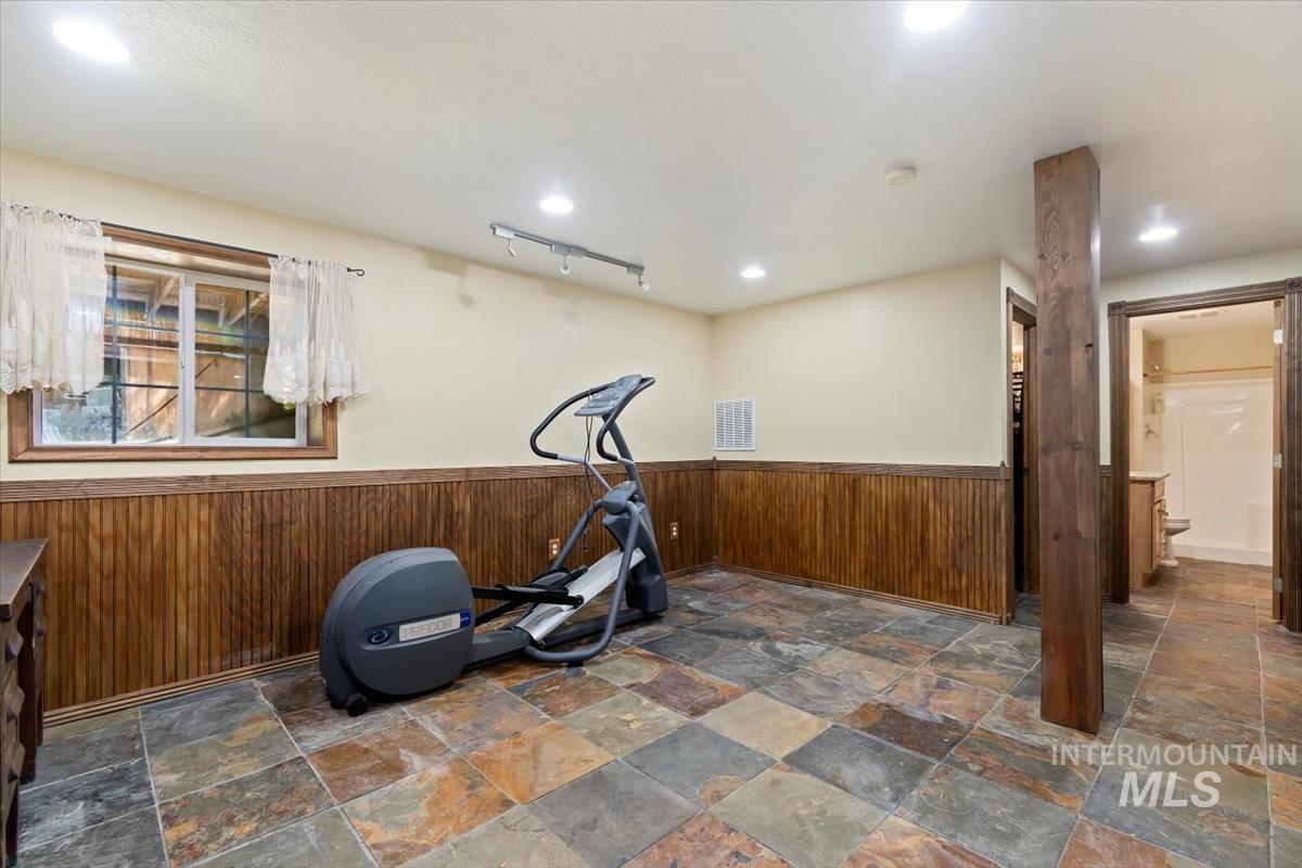 Exercise room with wooden walls, wainscoting, and recessed lighting