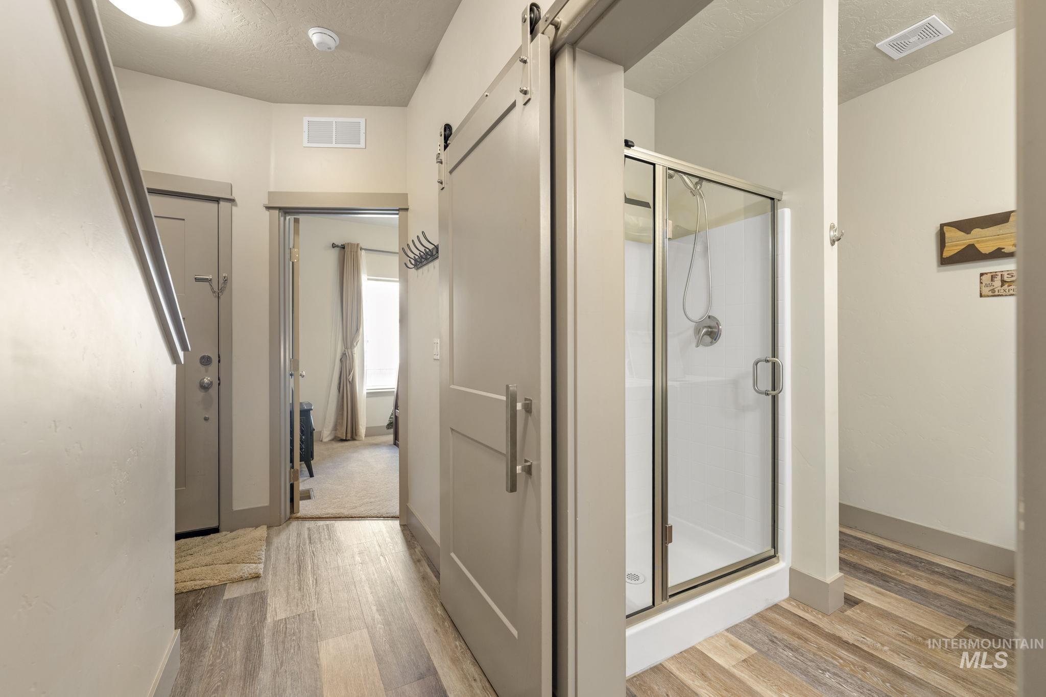 Full bathroom featuring a walk-in shower with a glass enclosure and a sliding barn door