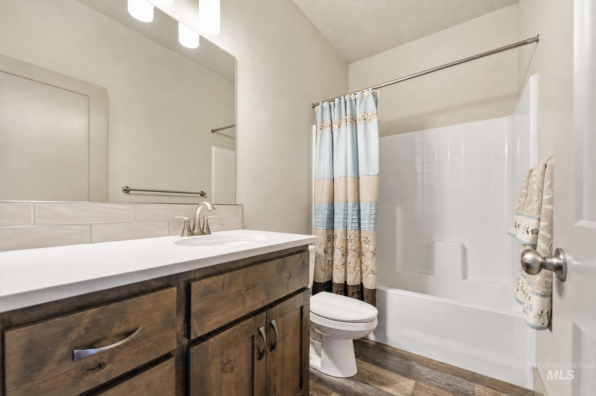 Bathroom featuring a wood-finish vanity with a white countertop, undermount sink, and brushed nickel faucet