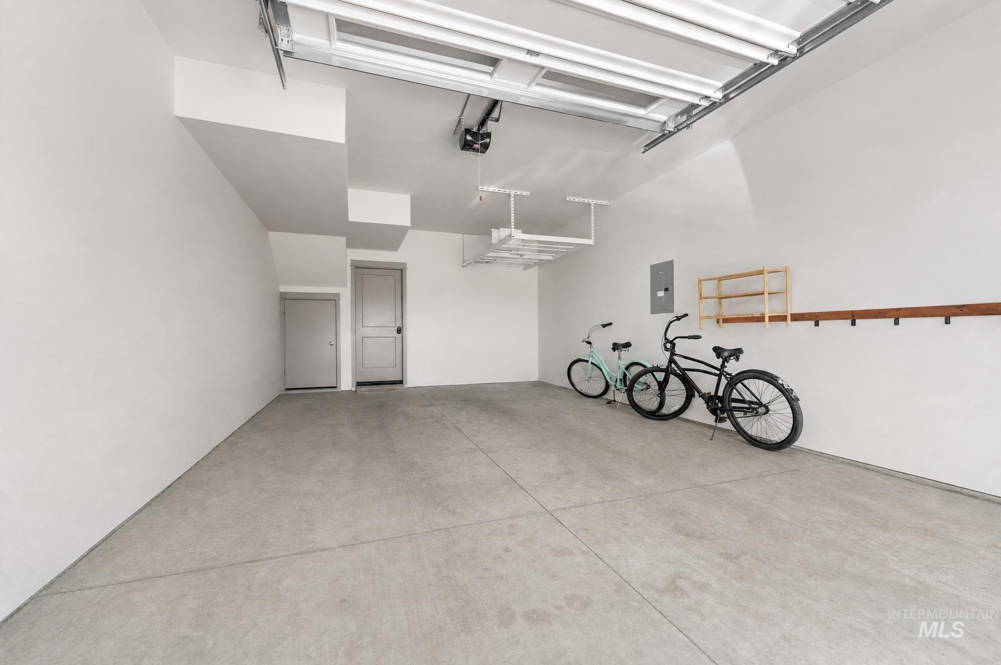 Spacious garage featuring a concrete floor, white walls, and an automatic overhead door