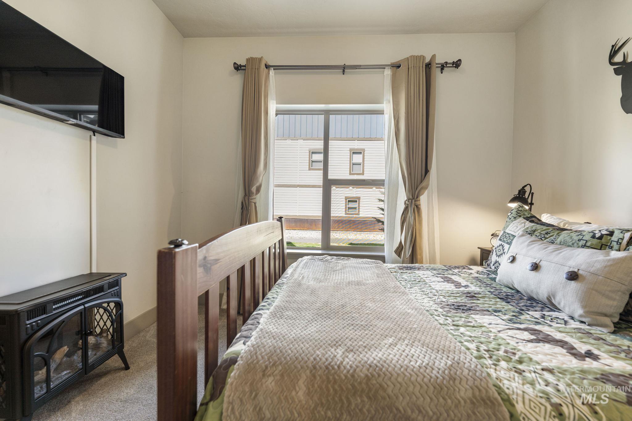 Carpeted room featuring a window with natural light, neutral wall paint, and an electric fireplace