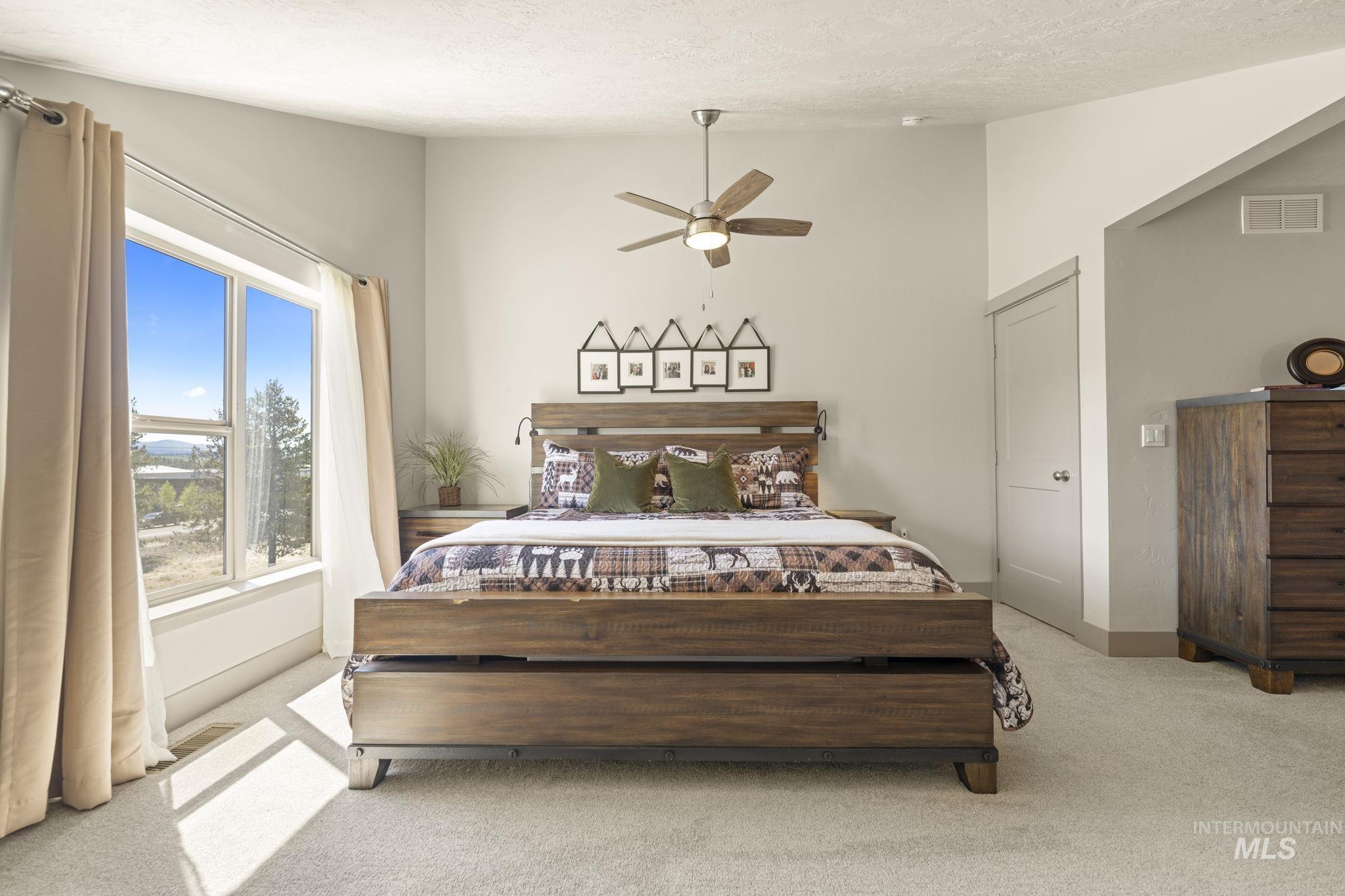 Spacious room featuring a large window, light-toned carpeting, a ceiling fan, a built-in wall niche, and a neutral color palette