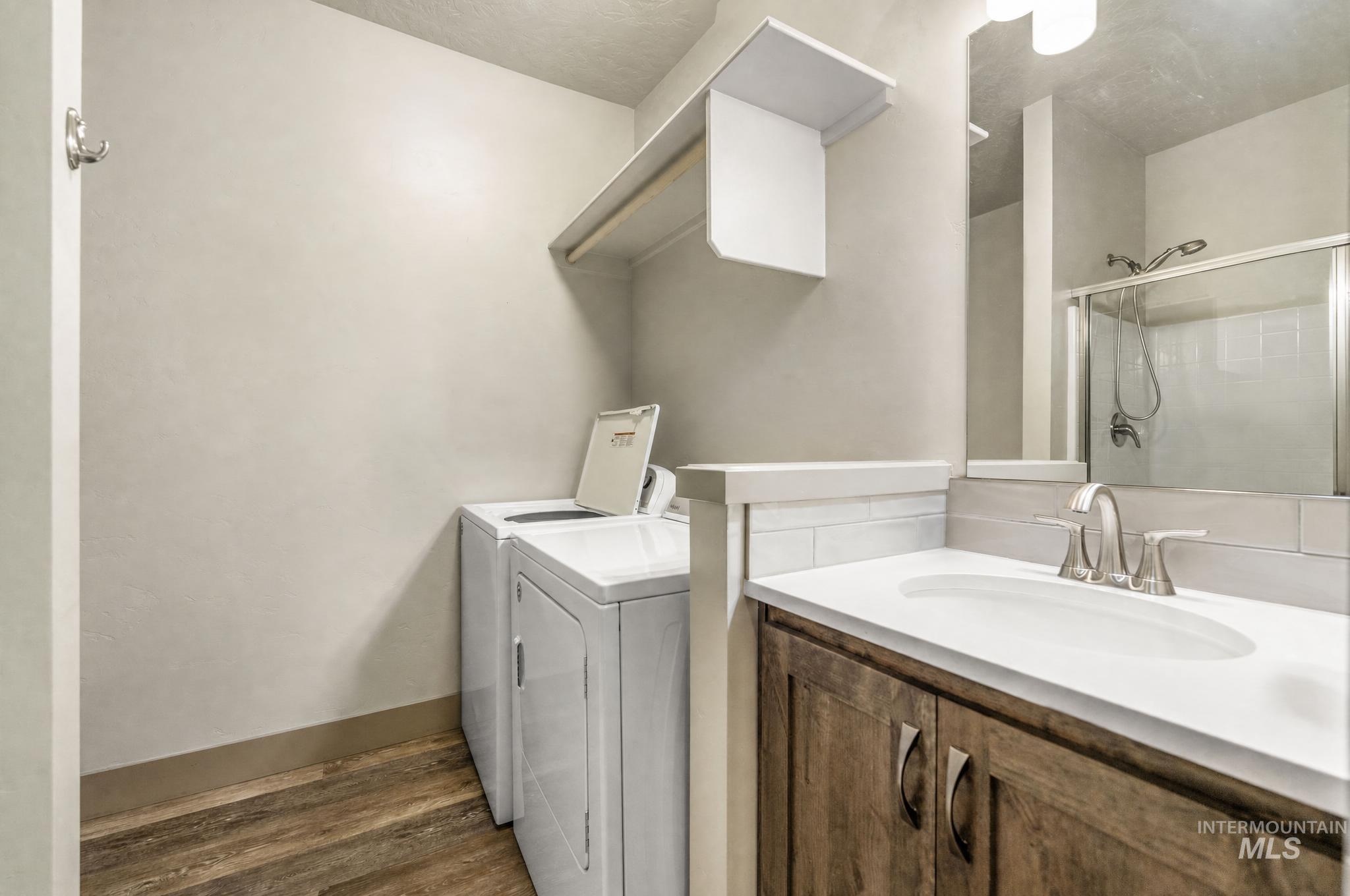 Bathroom featuring a wood-finish vanity with a white countertop and oval undermount sink, brushed nickel faucet, and a subway tile backsplash