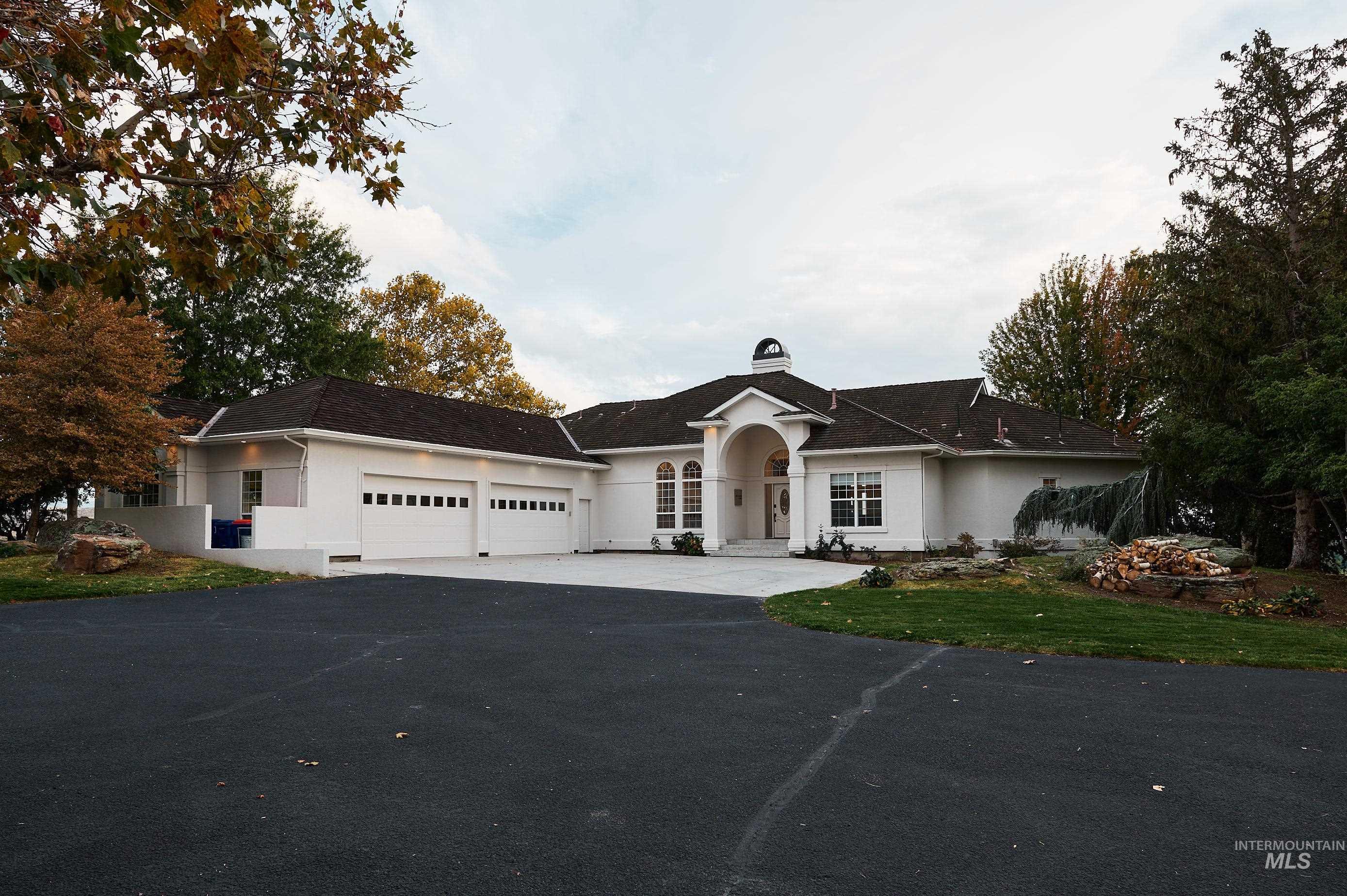 Ranch-style house featuring driveway, an attached garage, stucco siding, a front yard, and a chimney