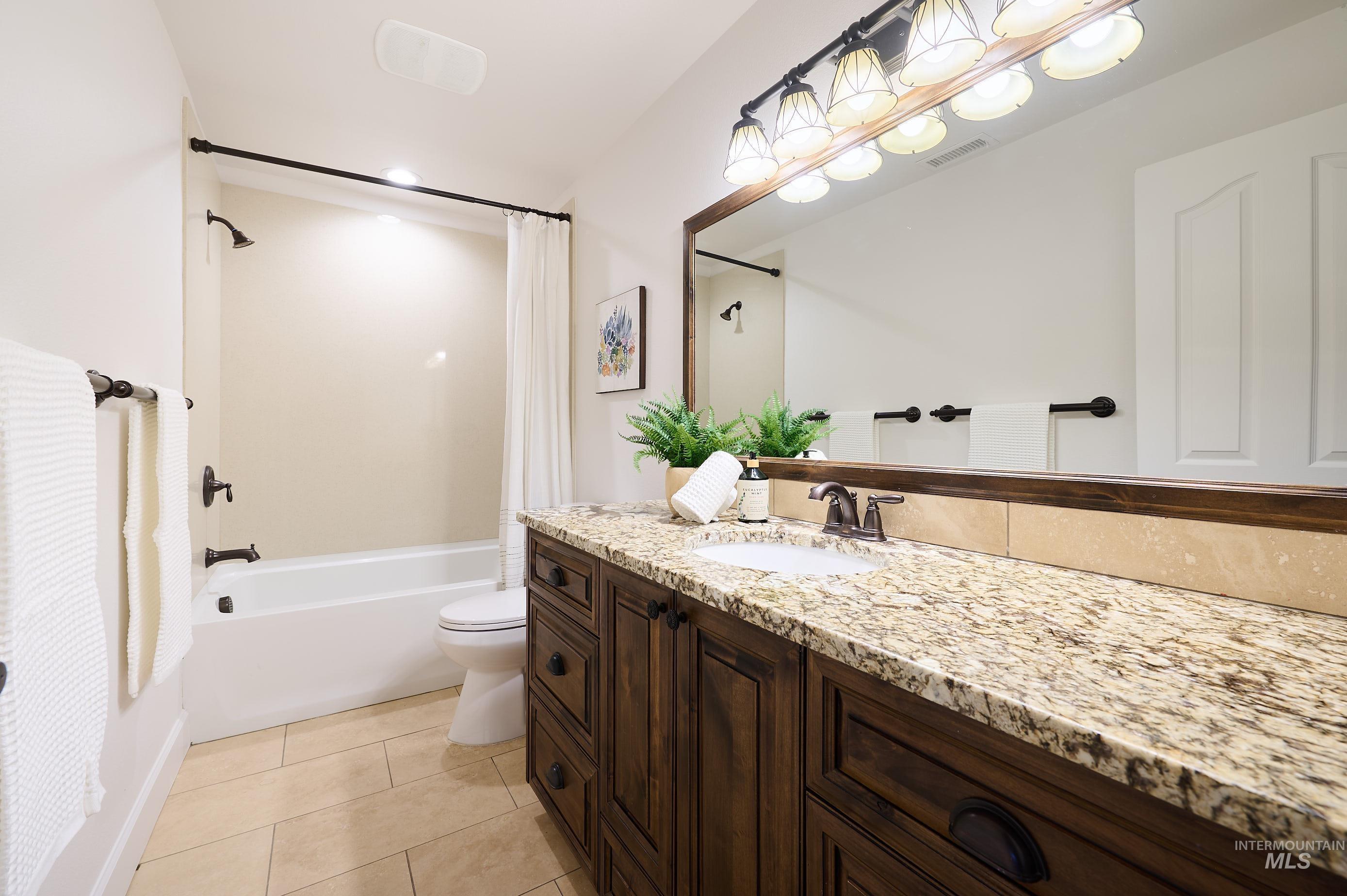 Full bathroom featuring shower / bath combo, vanity, and light tile patterned floors