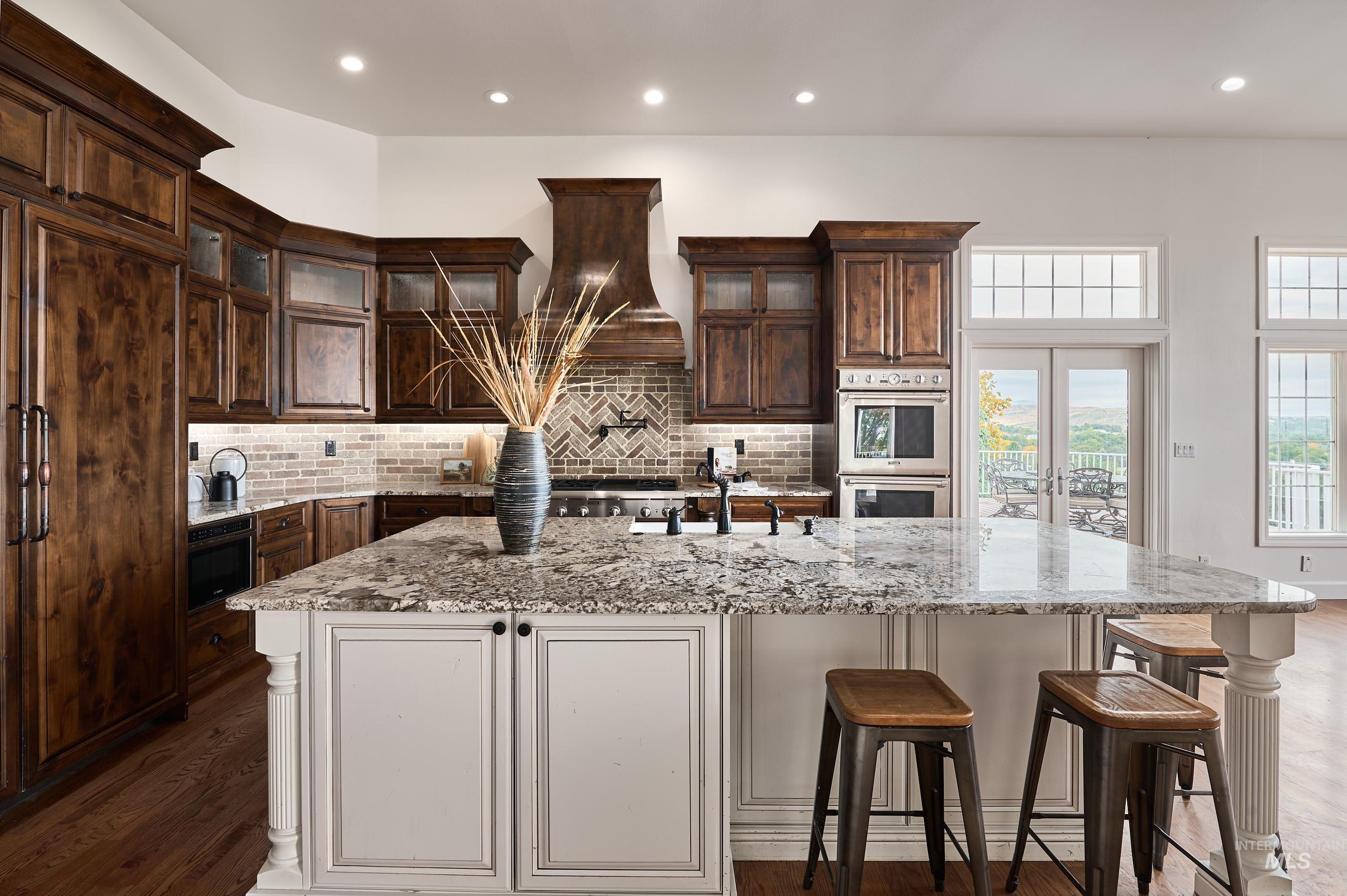 Kitchen with glass insert cabinets, light stone counters, a breakfast bar area, dark wood-style floors, and white cabinetry