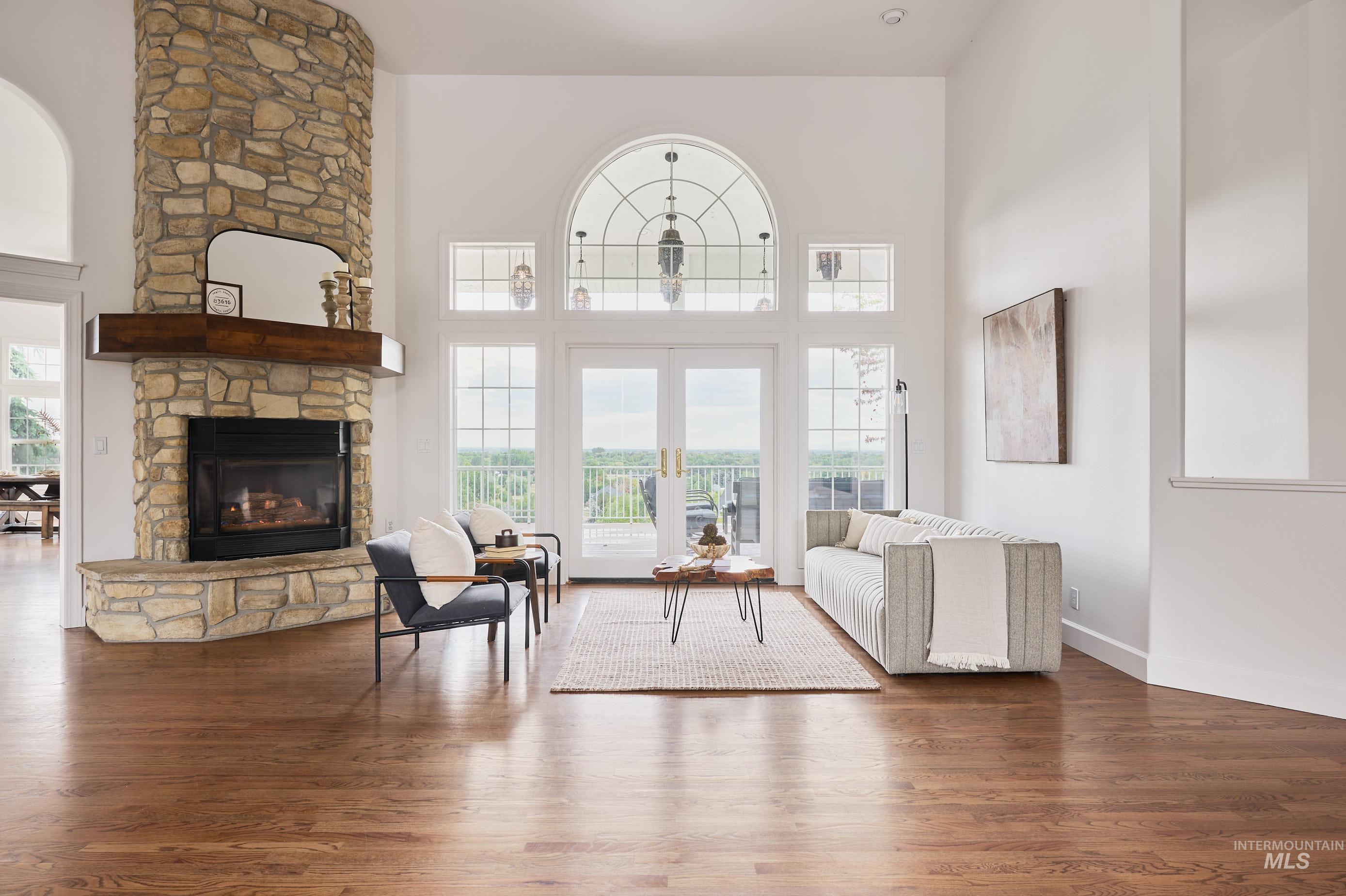 Living area featuring wood finished floors, a fireplace, a towering ceiling, and french doors