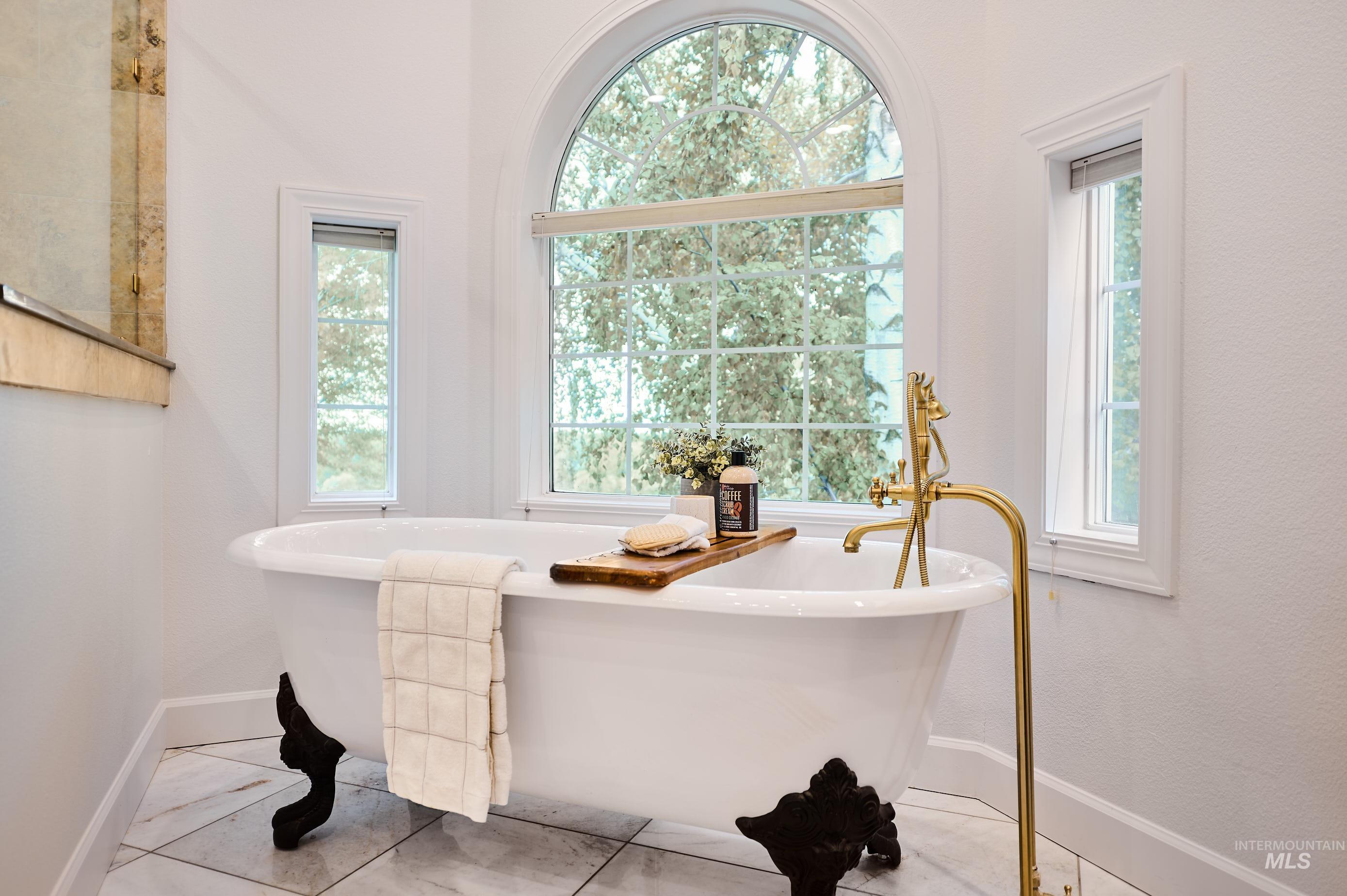 Bathroom featuring a freestanding bath, healthy amount of natural light, and light tile patterned floors