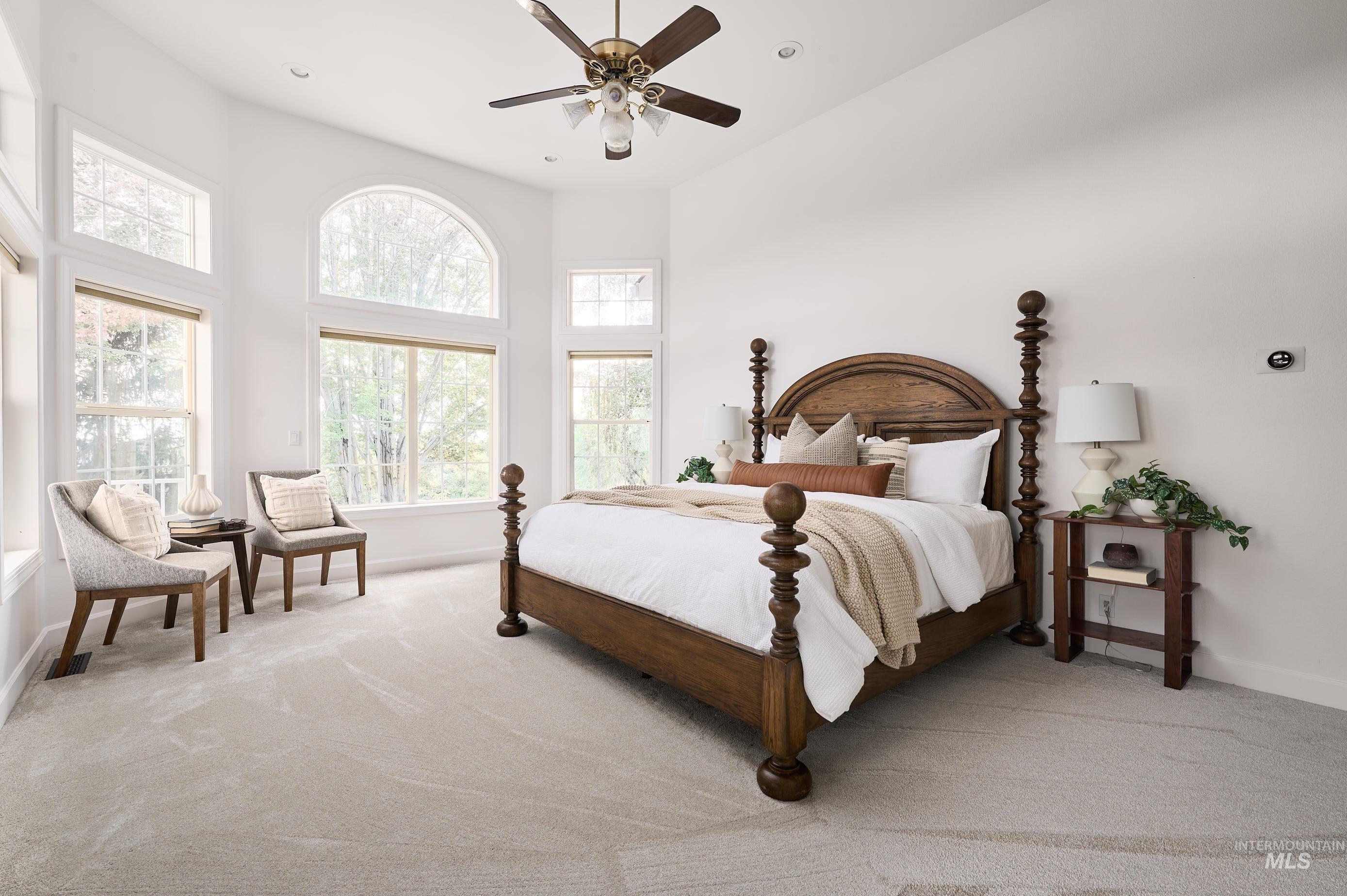 Bedroom featuring light colored carpet, a ceiling fan, recessed lighting, and a towering ceiling