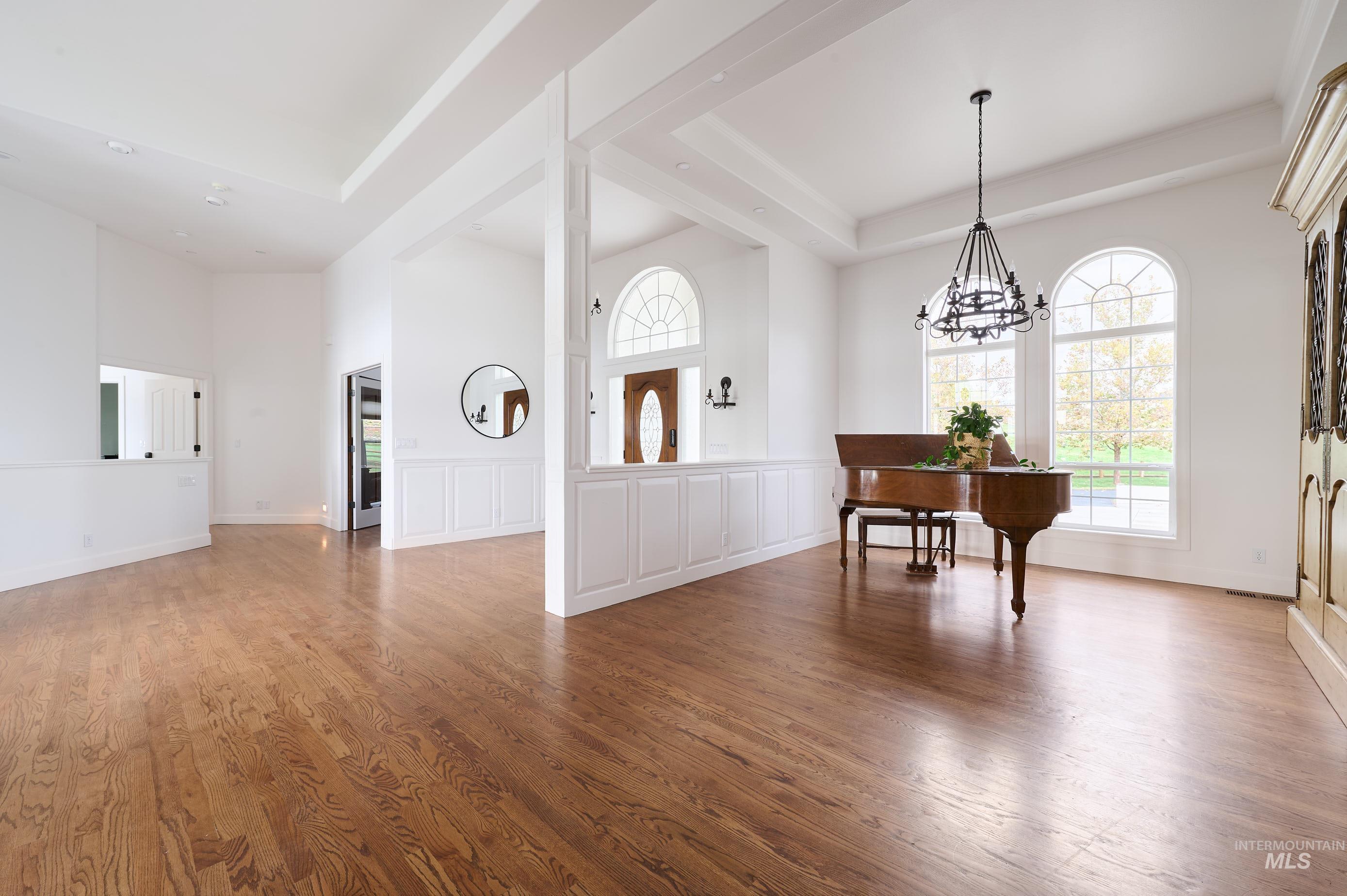 Entryway featuring healthy amount of natural light, a tray ceiling, light wood finished floors, a high ceiling, and a chandelier