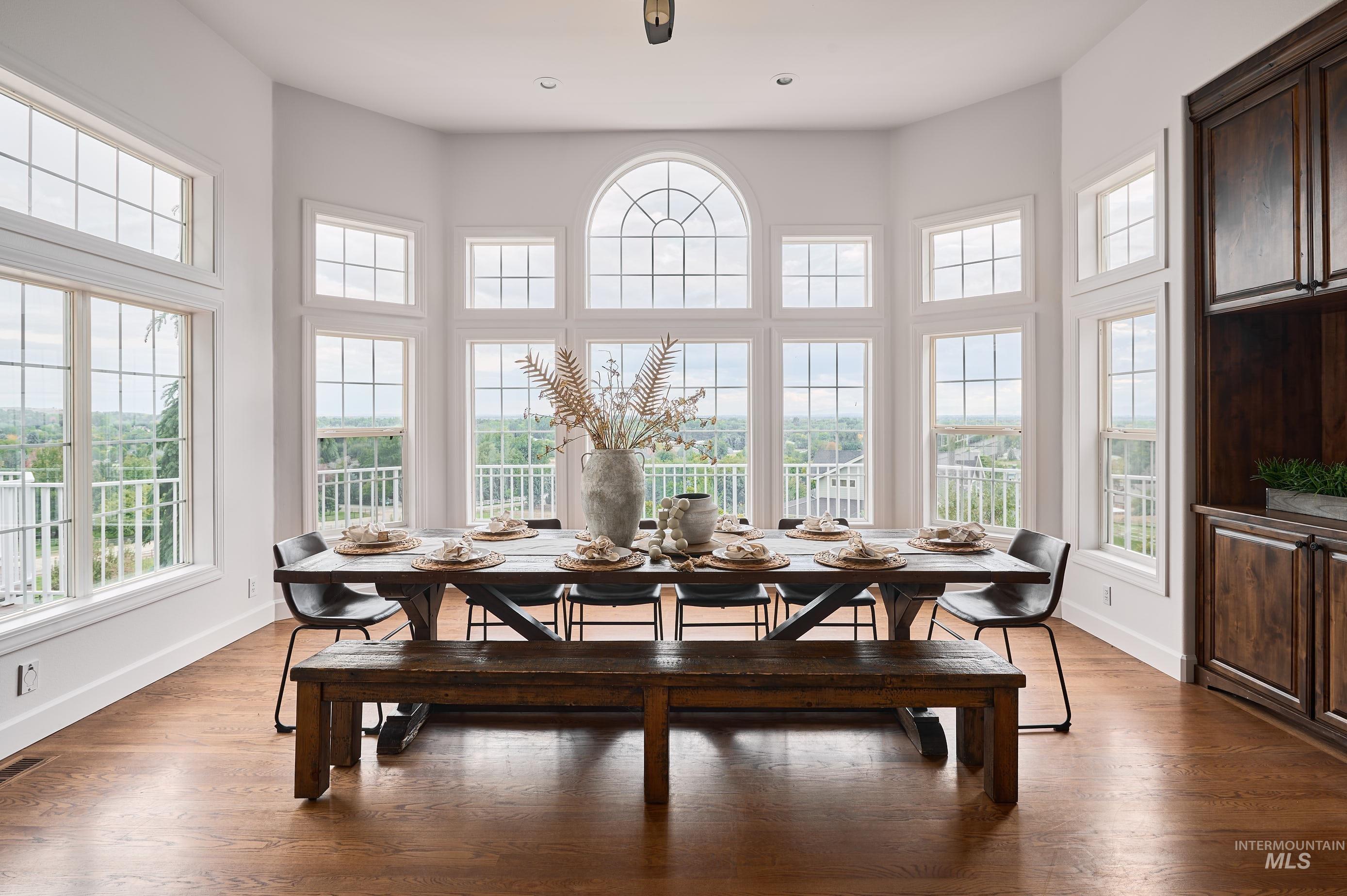 Dining area featuring dark wood-style flooring, plenty of natural light, and a high ceiling