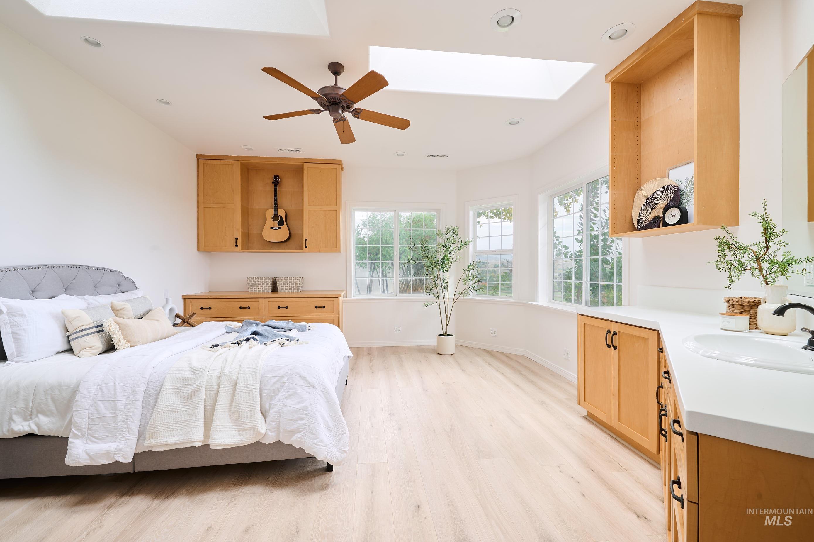 Bedroom featuring a skylight, light wood-style floors, recessed lighting, and a ceiling fan