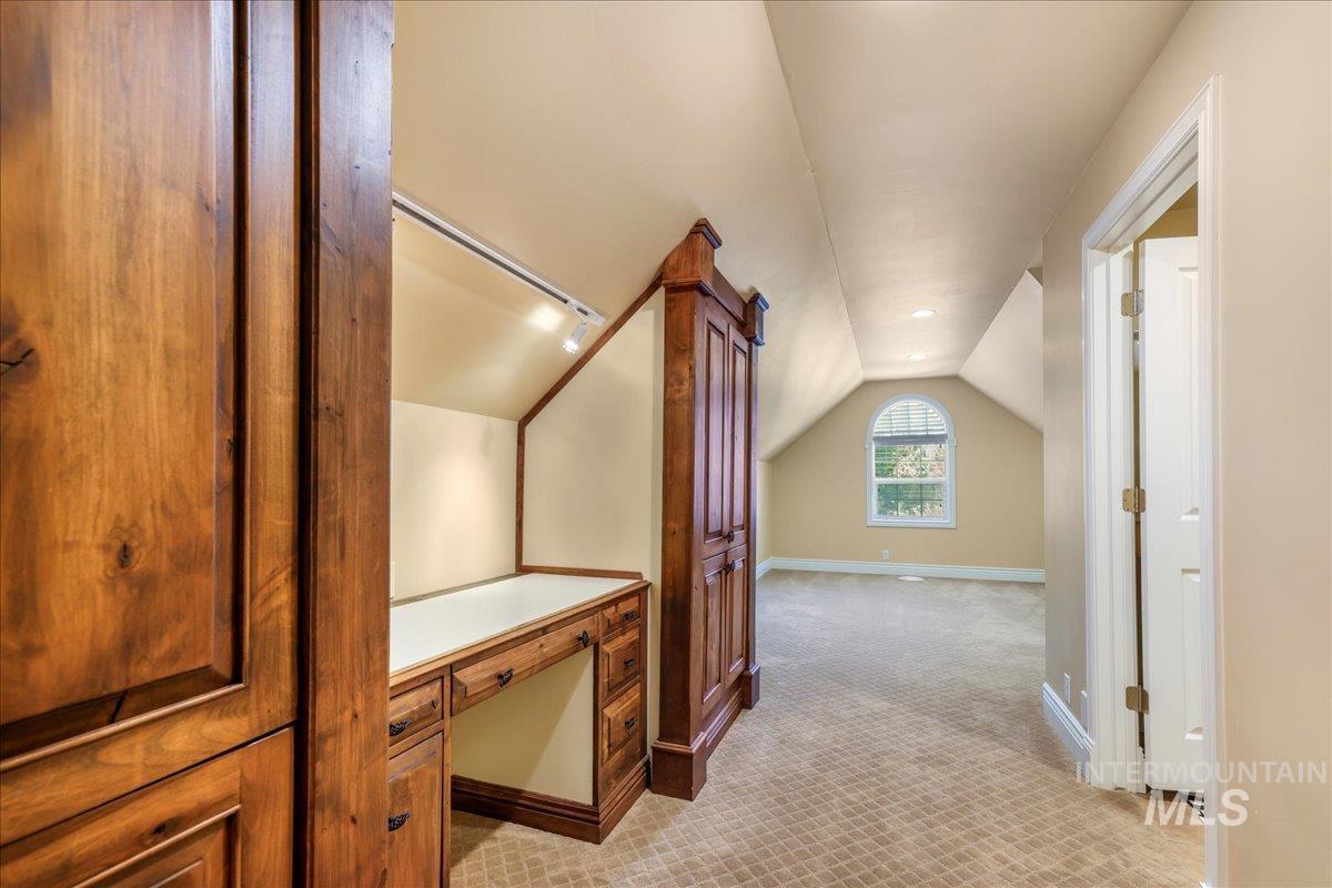 Hall with lofted ceiling and light colored carpet