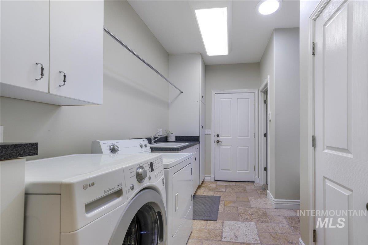 Laundry area with stone tile flooring, cabinet space, and independent washer and dryer