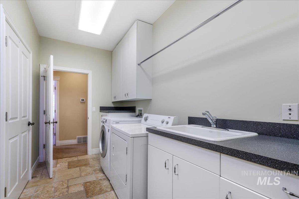 Laundry area featuring washer and clothes dryer, stone tile flooring, and cabinet space