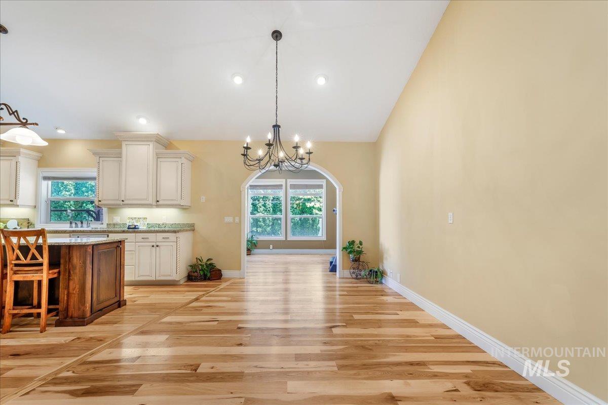 Kitchen with plenty of natural light, light wood-type flooring, a chandelier, decorative light fixtures, and recessed lighting