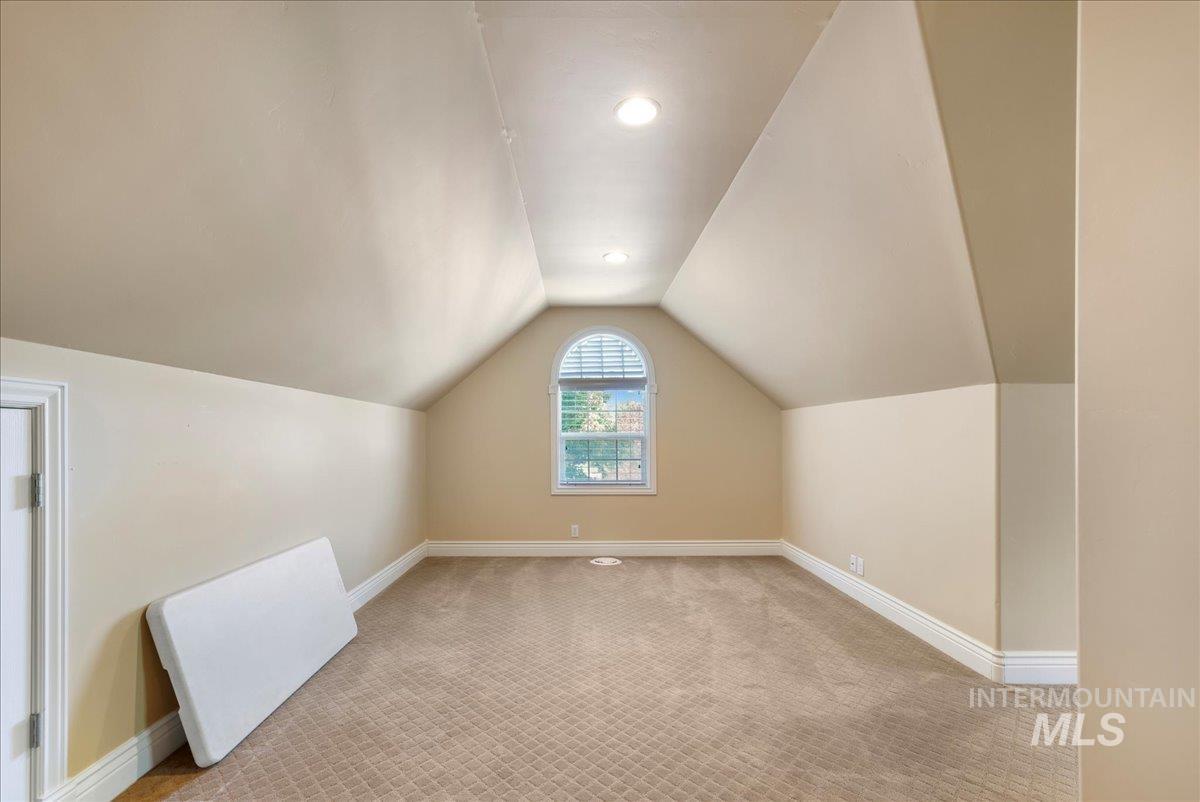 Additional living space with vaulted ceiling and light carpet