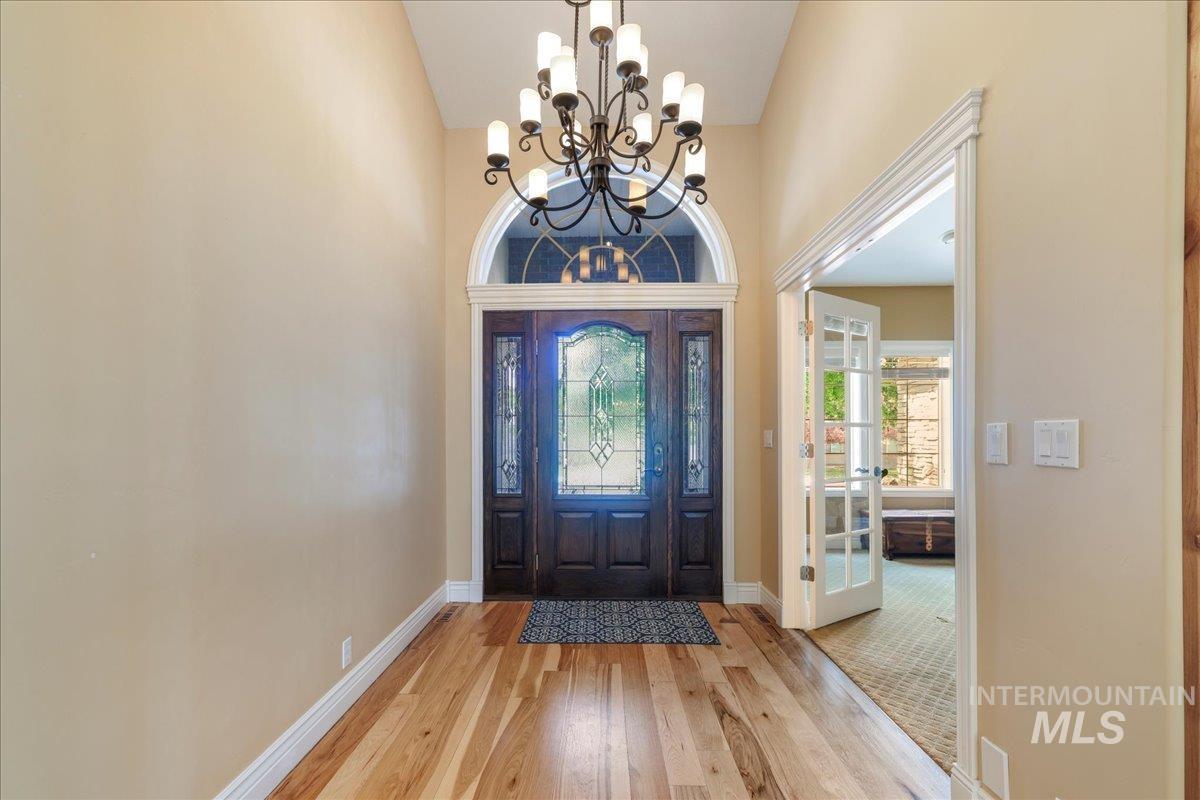 Foyer featuring a chandelier, light wood-type flooring, and a towering ceiling