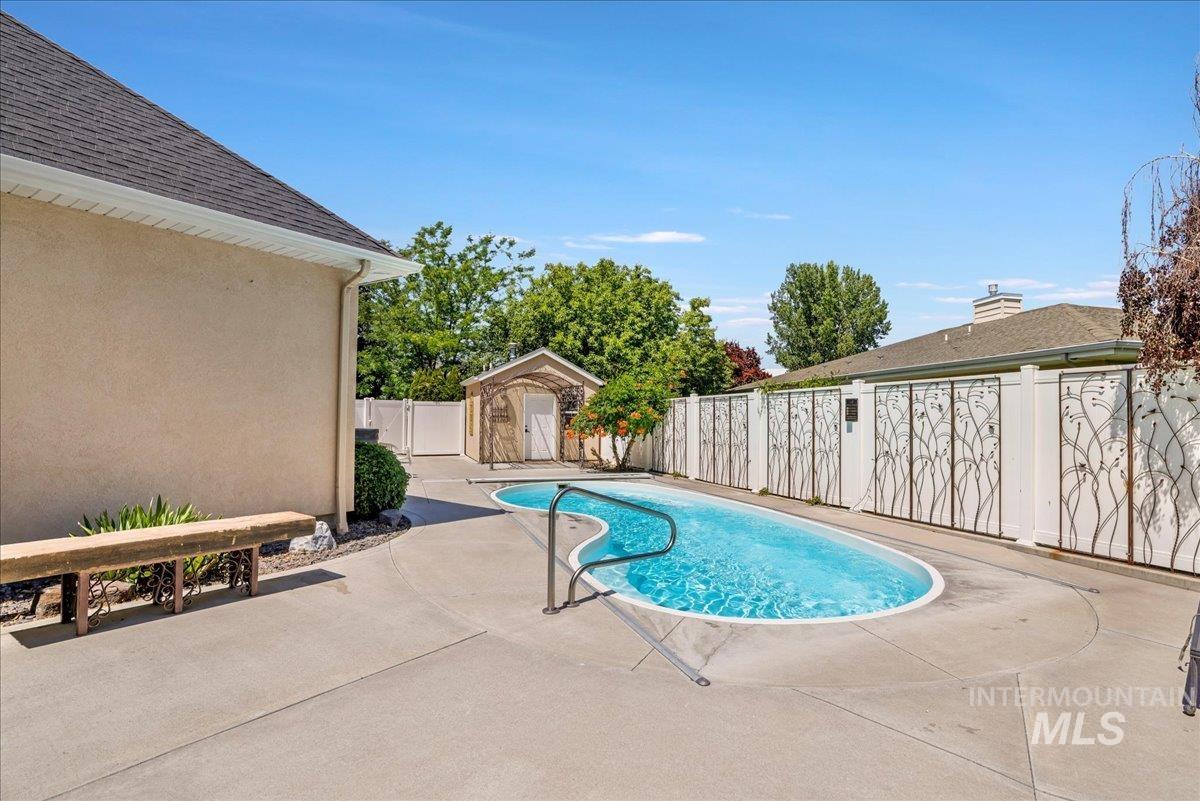 View of pool featuring a patio area, a fenced backyard, and a storage shed
