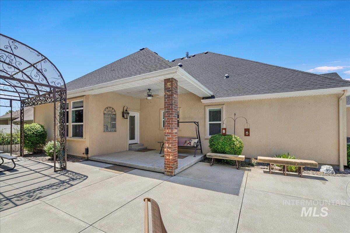 Rear view of property featuring a shingled roof, stucco siding, a patio, and a ceiling fan