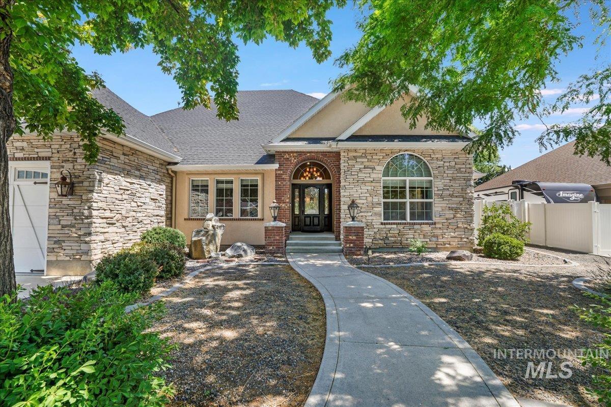 View of front of house featuring stone siding and roof with shingles