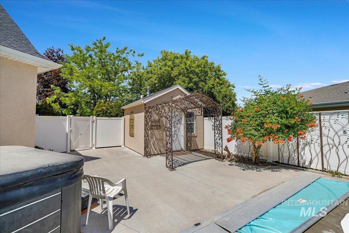 Fenced backyard with a gate, a hot tub, and a patio