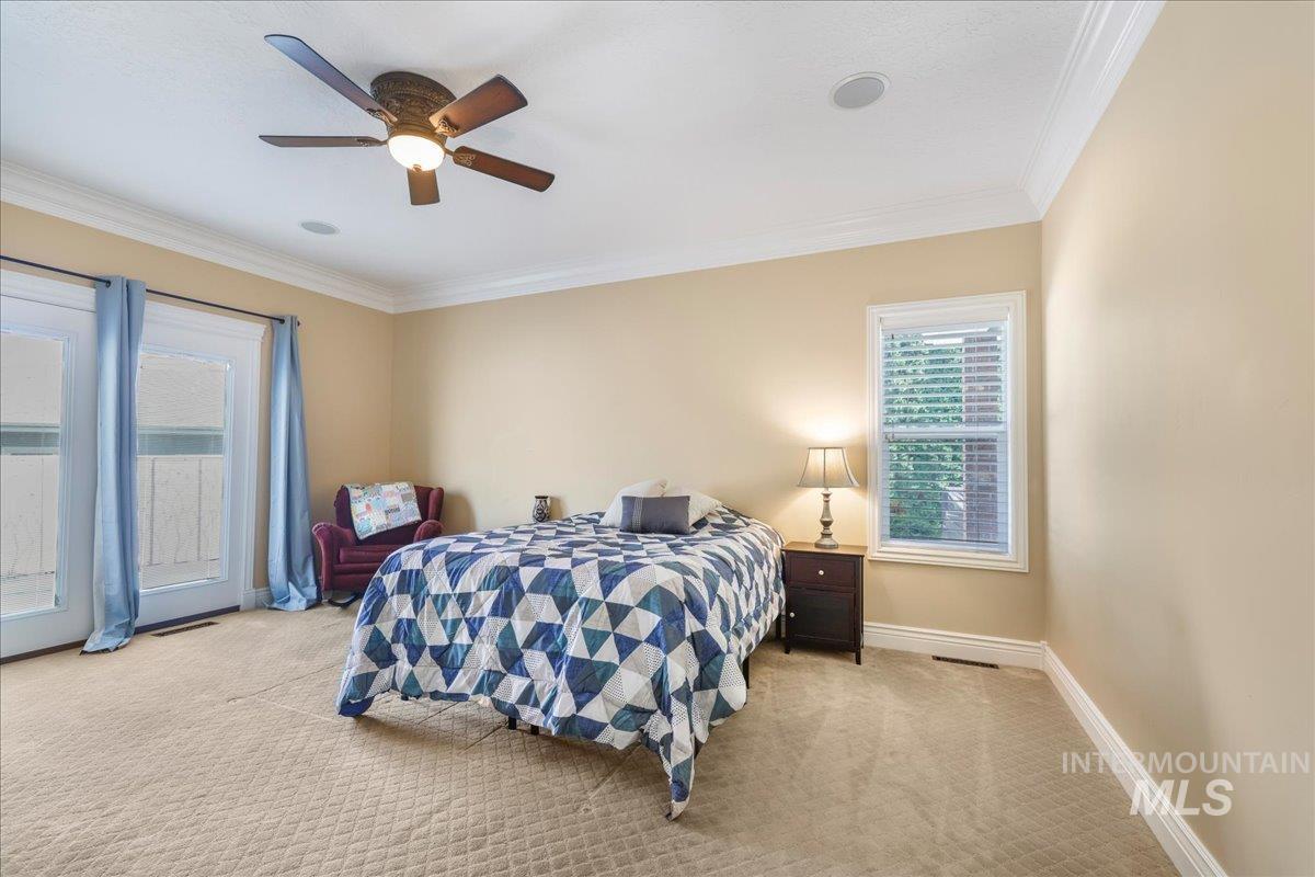 Bedroom with carpet, ornamental molding, and ceiling fan