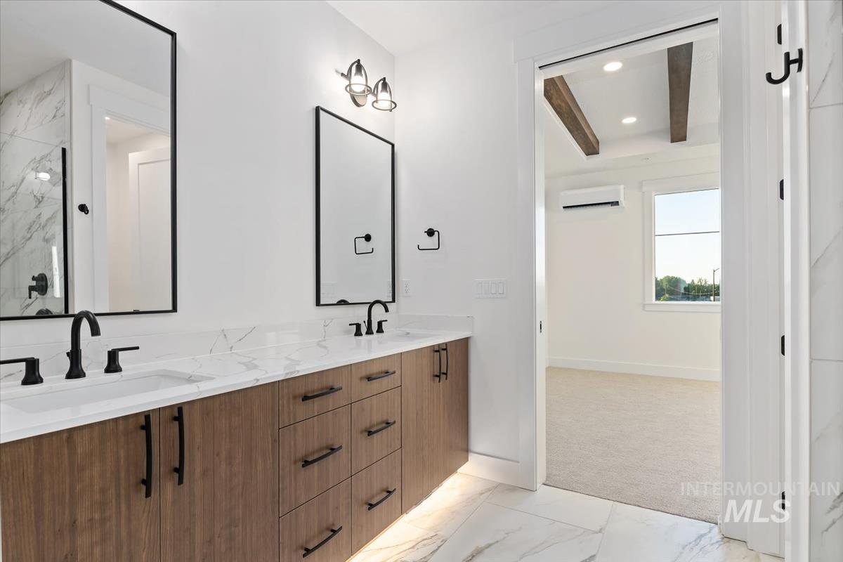 Bathroom featuring light marble finish flooring, double vanity, recessed lighting, an AC wall unit, and a marble finish shower