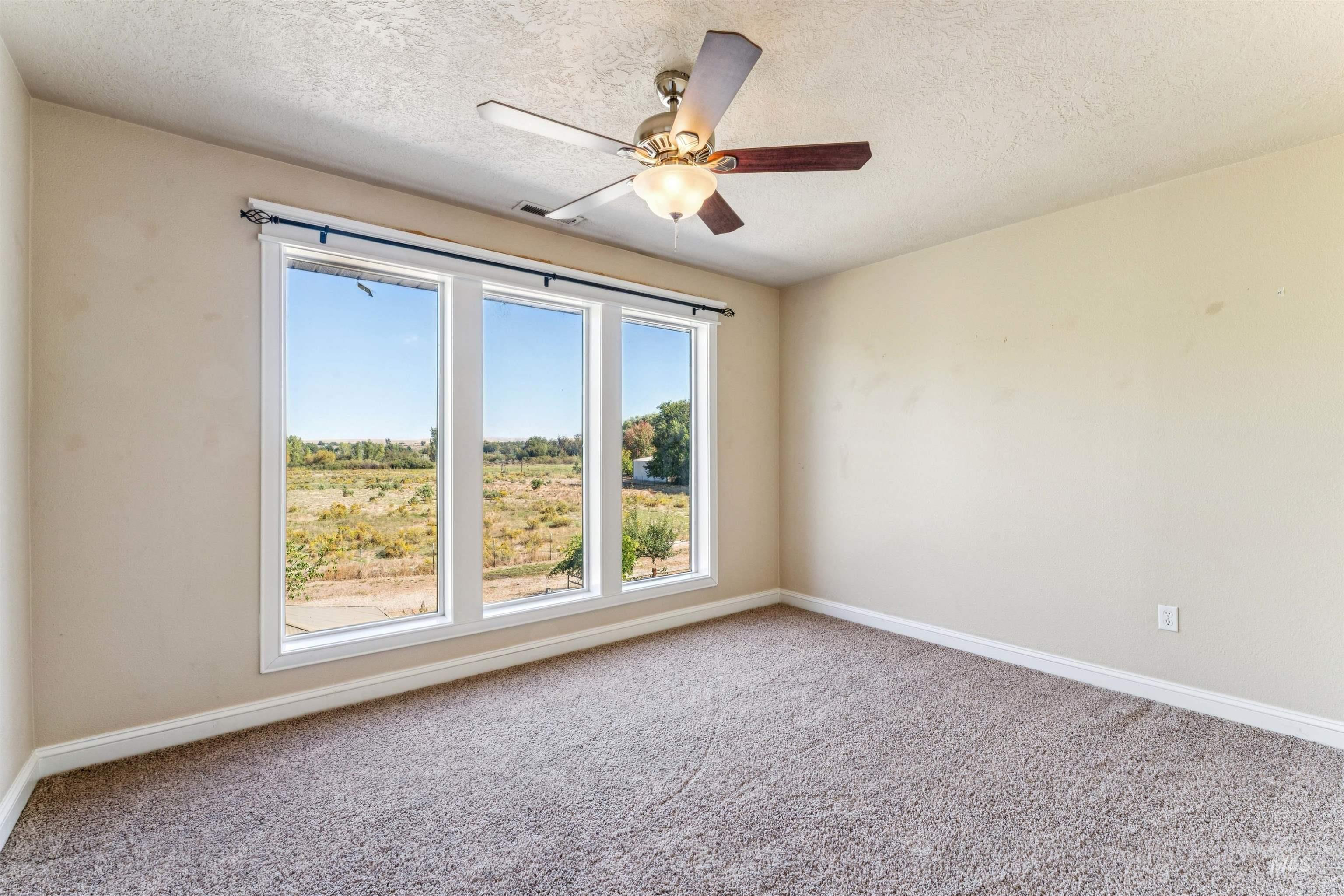 Carpeted spare room featuring a textured ceiling and a ceiling fan