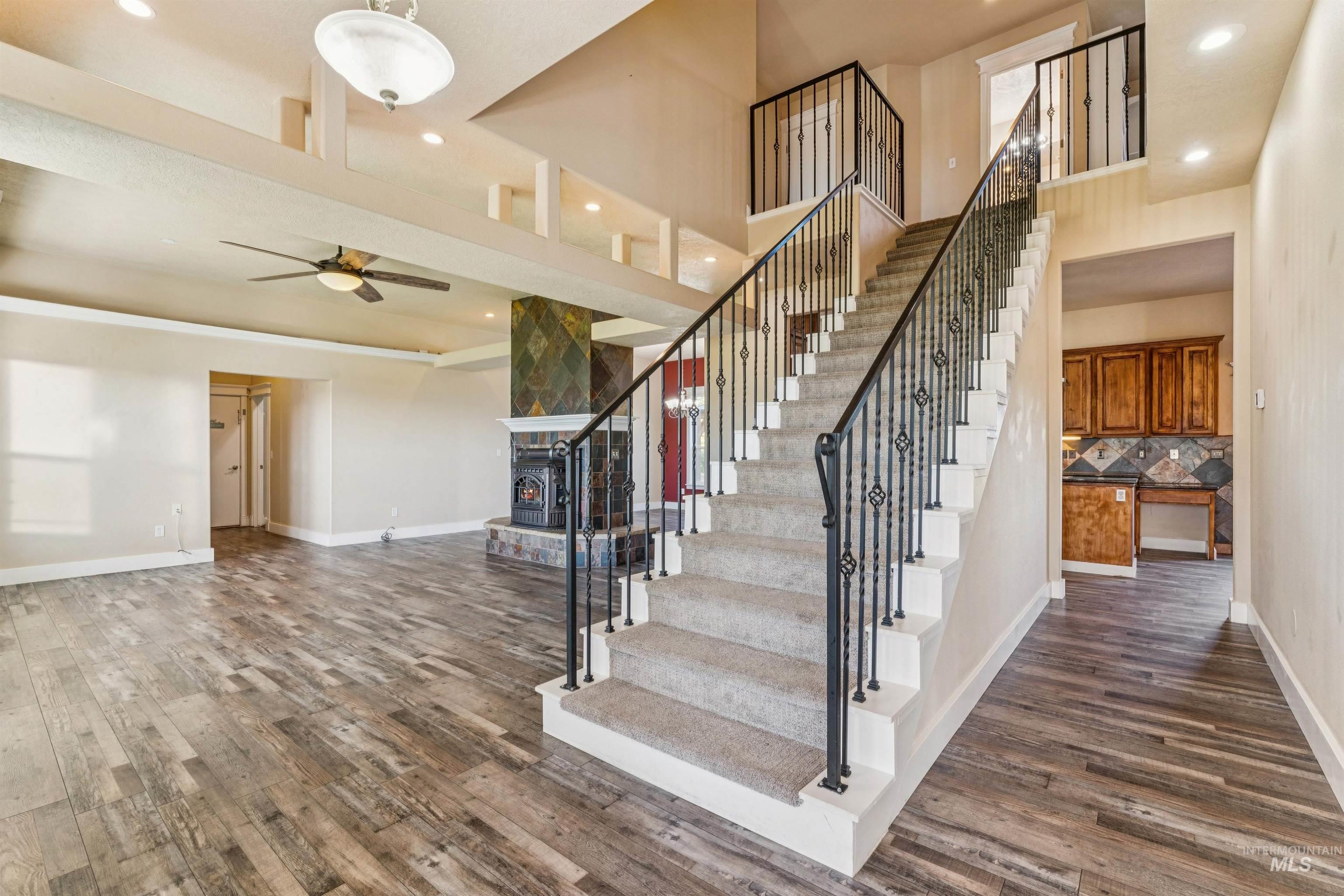 Staircase with wood finished floors, recessed lighting, a towering ceiling, and a ceiling fan