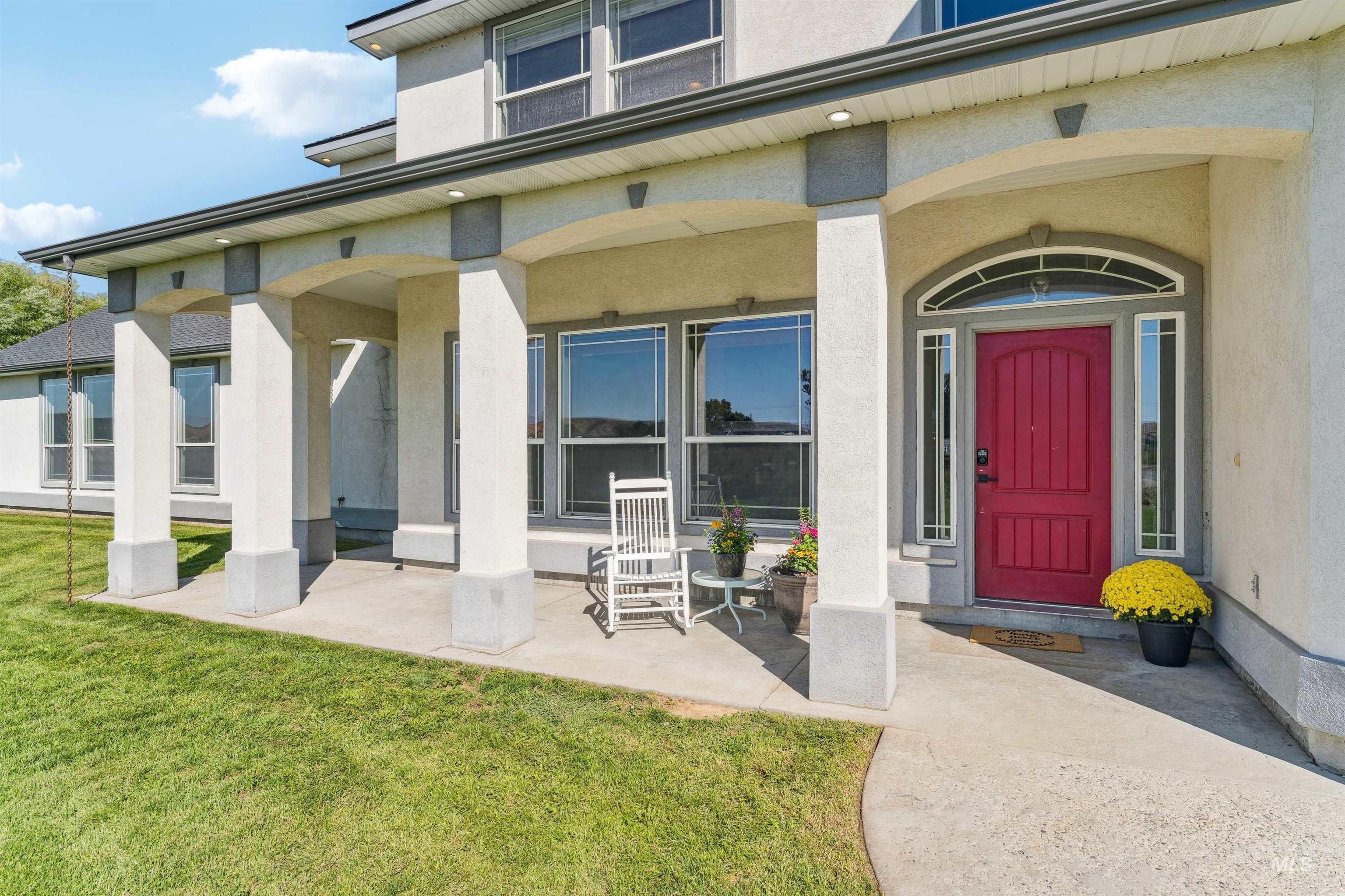 Entrance to property featuring stucco siding, a lawn, and a porch