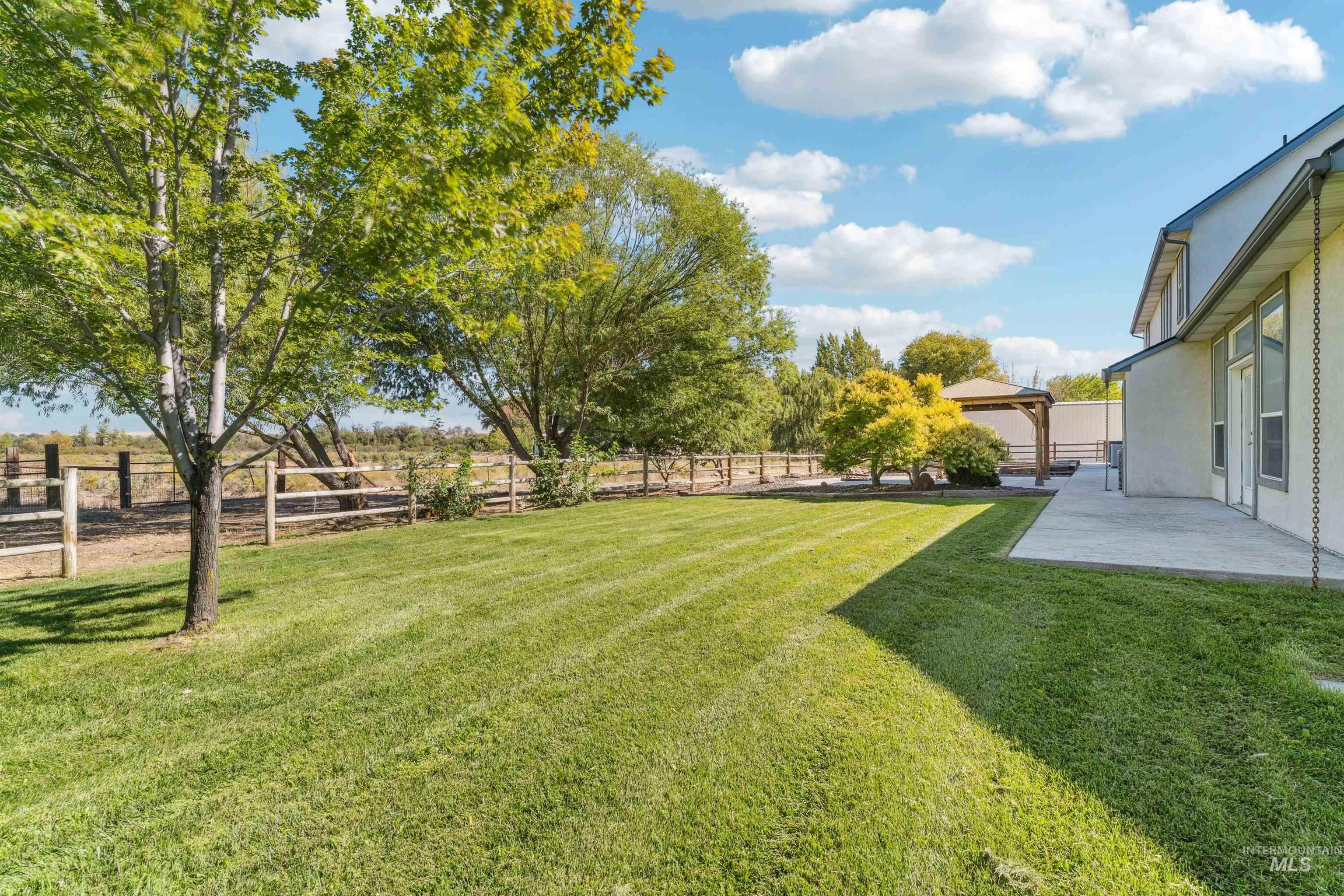 Fenced backyard featuring a gazebo, a patio area, and a view of countryside